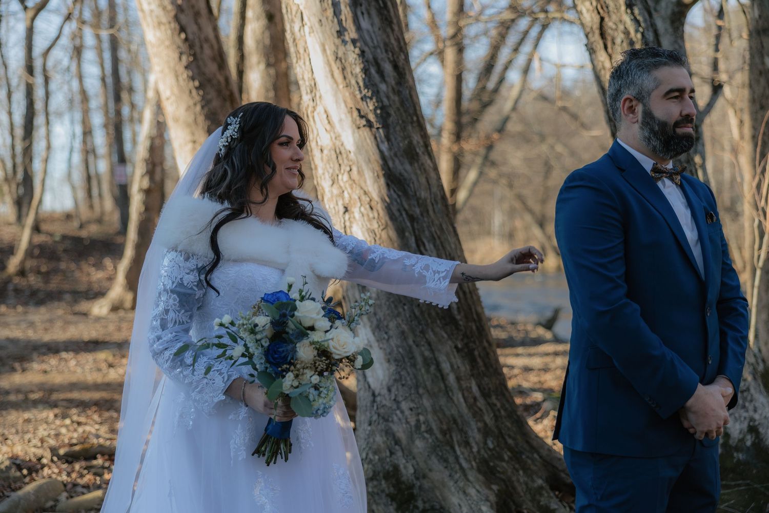 Wedding couple poses together in a wooded outdoor setting during their ceremony.