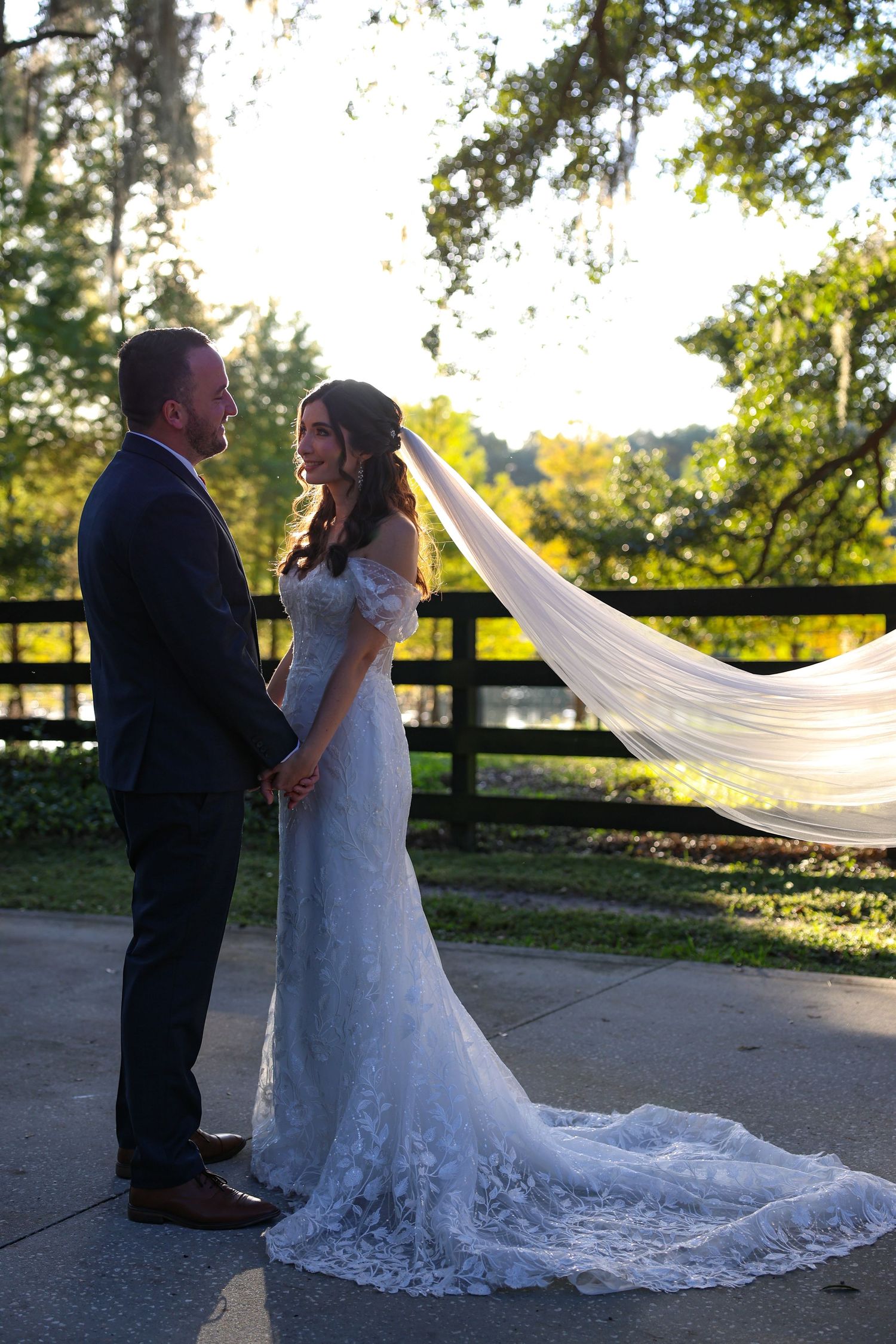 Dramatic sunset wedding portraits with flowing veil and natural backlight.