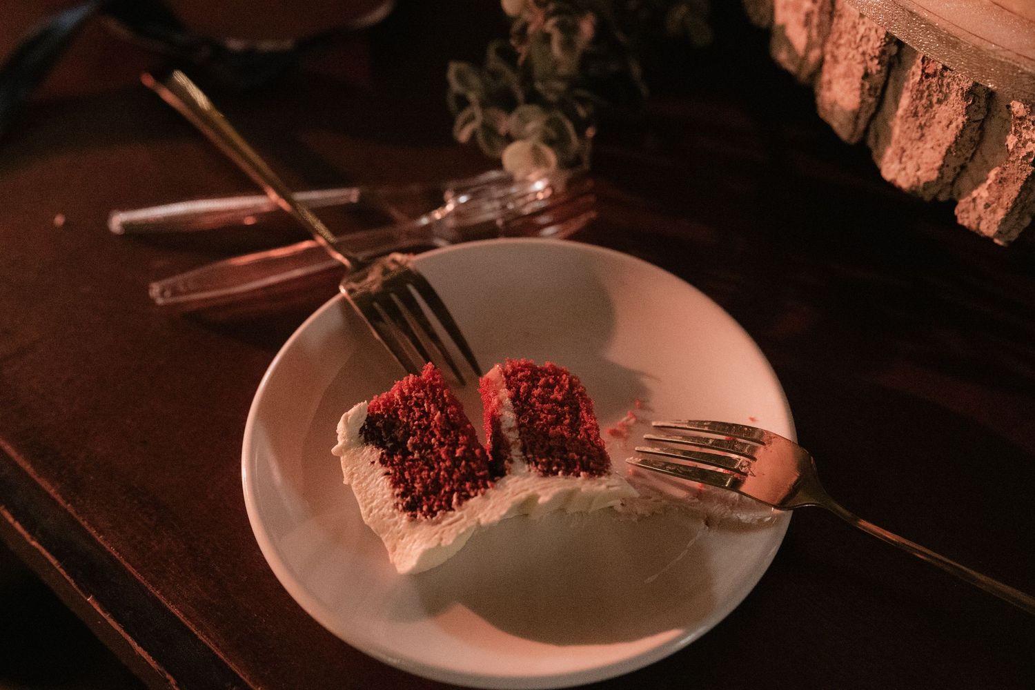 Close-up of red velvet cake being cut on a white plate.