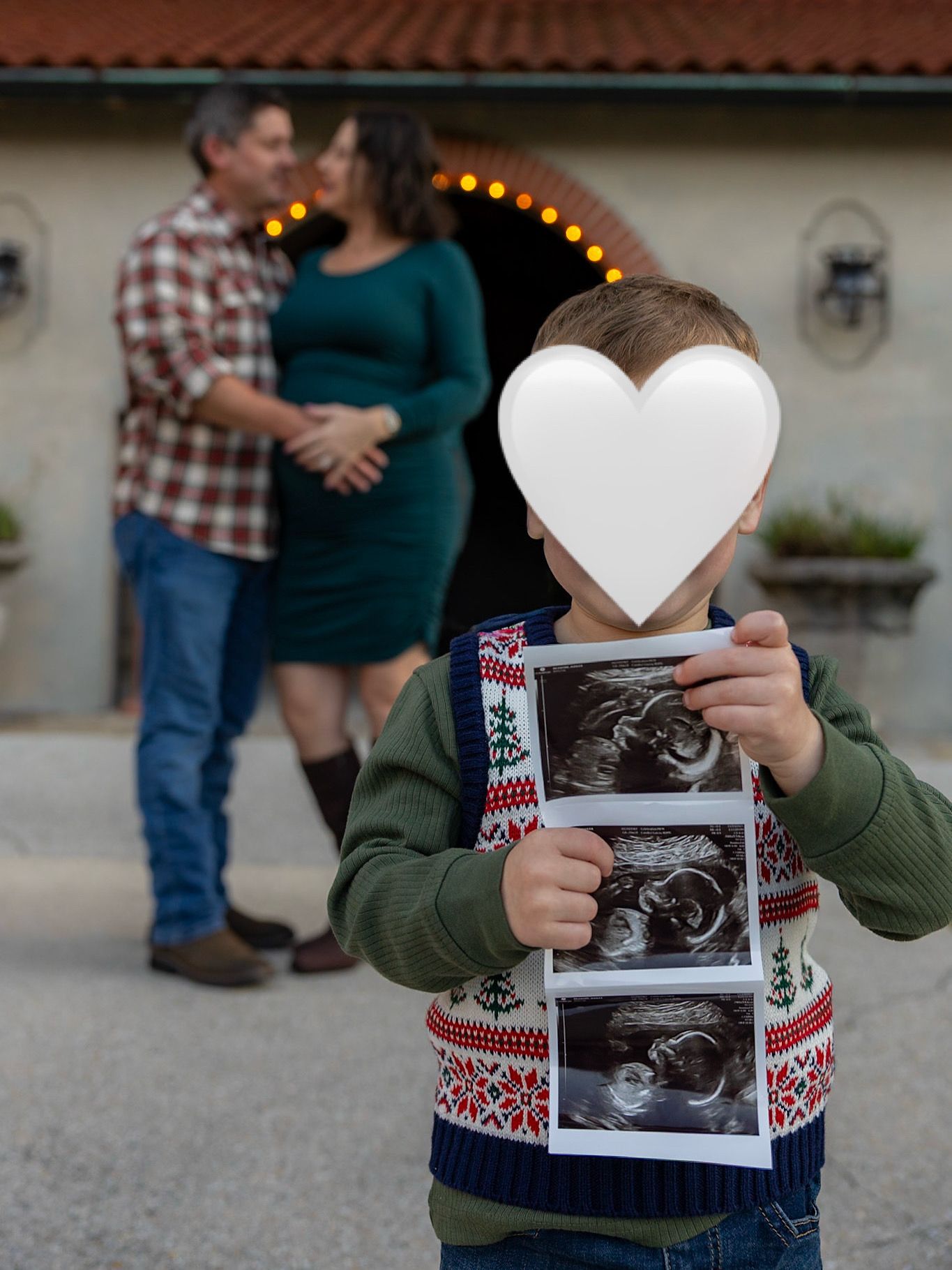 Someone holds up ultrasound photos with heart-shaped paper decorations in a pregnancy announcement.