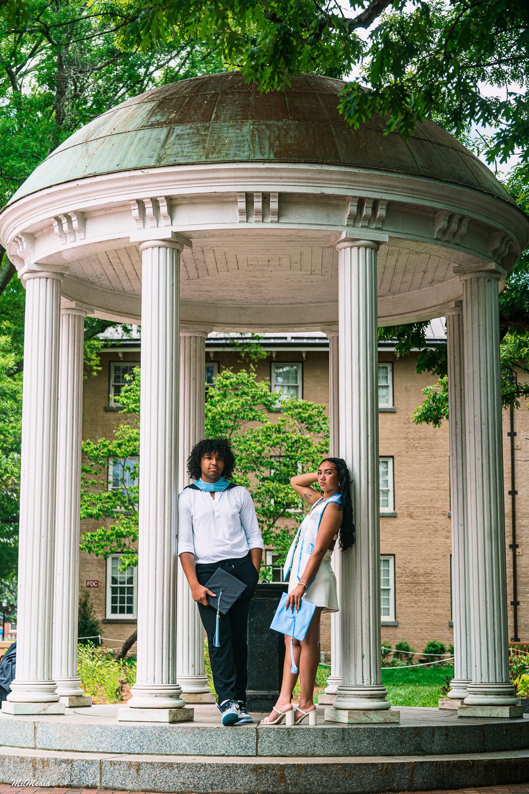 Couple poses in a classical domed gazebo with white columns on a university campus.
