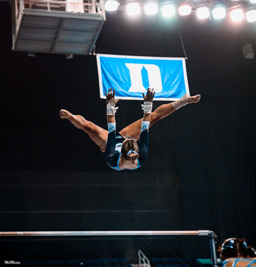 Gymnast performs a graceful aerial routine on the uneven bars during a competition.