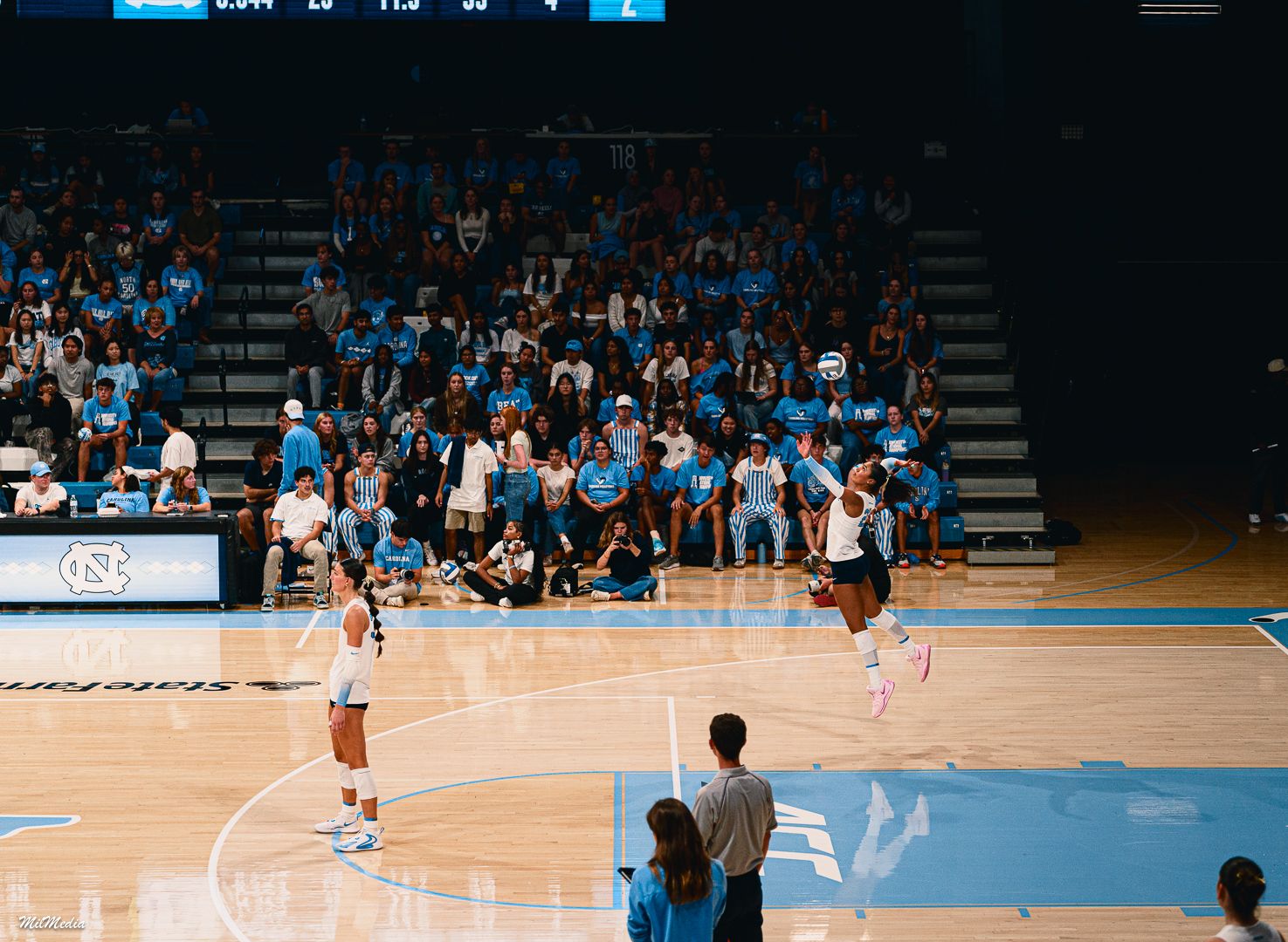 Wide shot of volleyball court during UNC game with players in action.