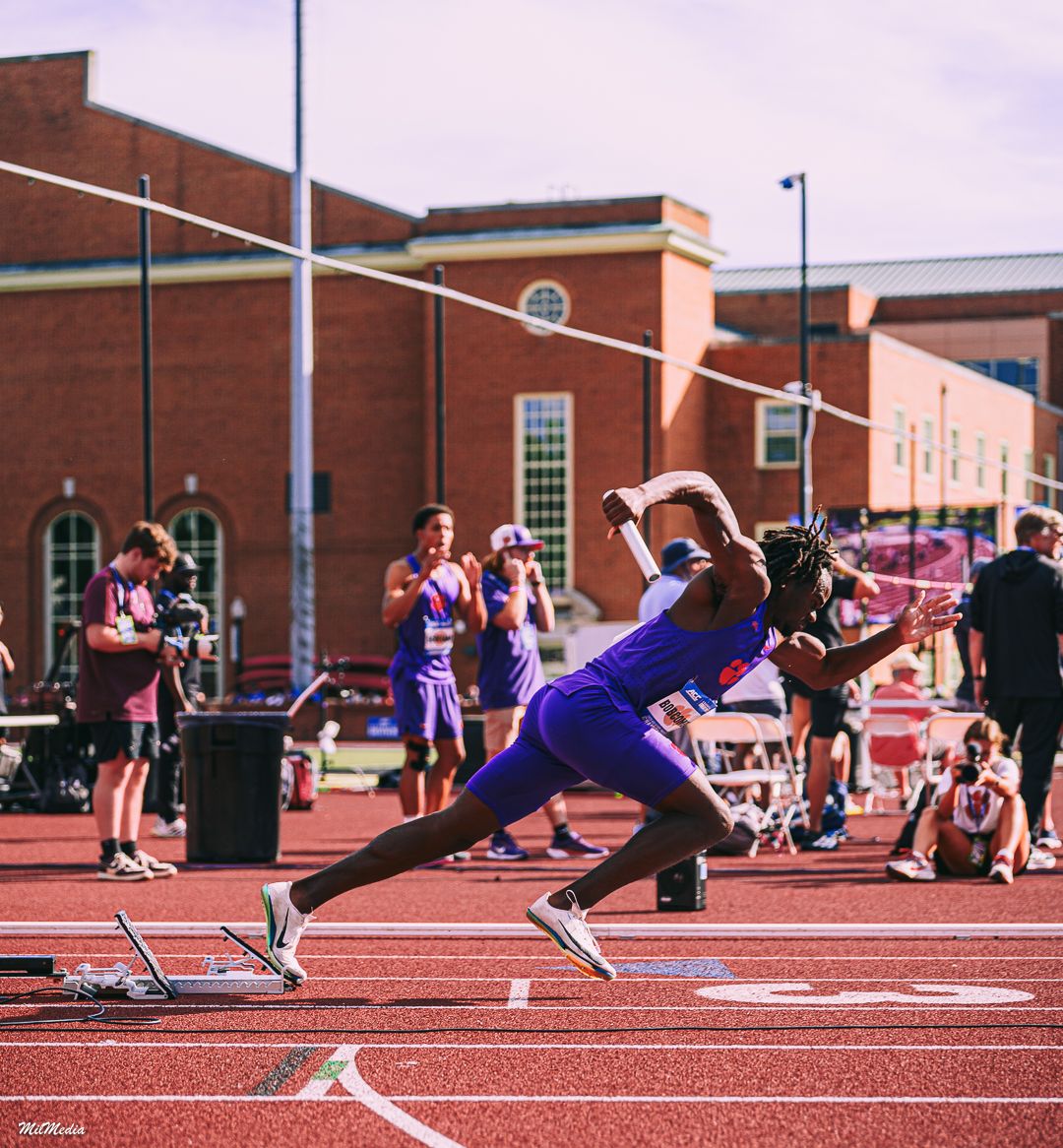 Athletes dive towards the finish line on a red track during an intense sprint race competition during the ACC Track and Field Championships.