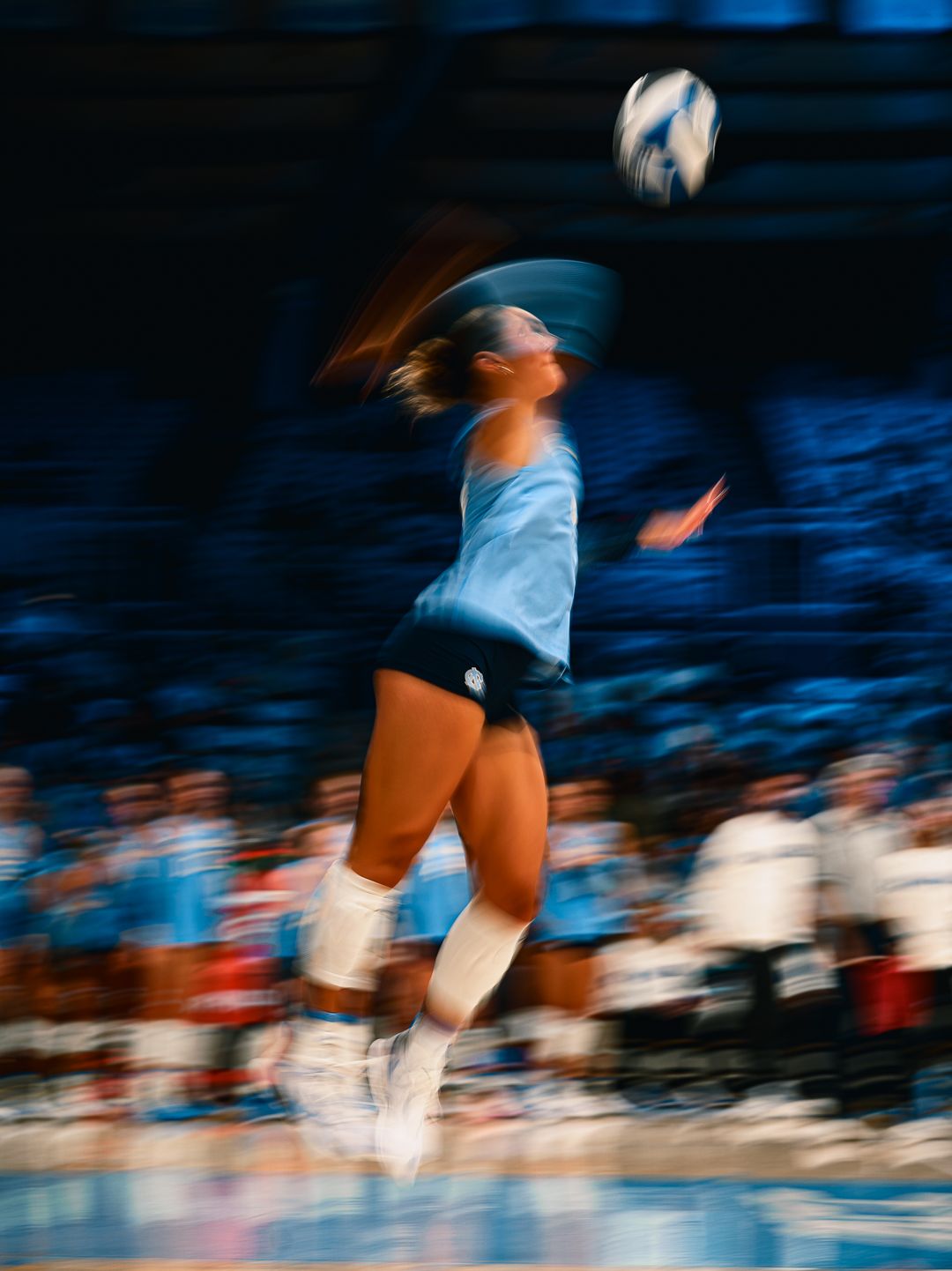 Motion blur capture of volleyball players diving for the ball during intense game action.