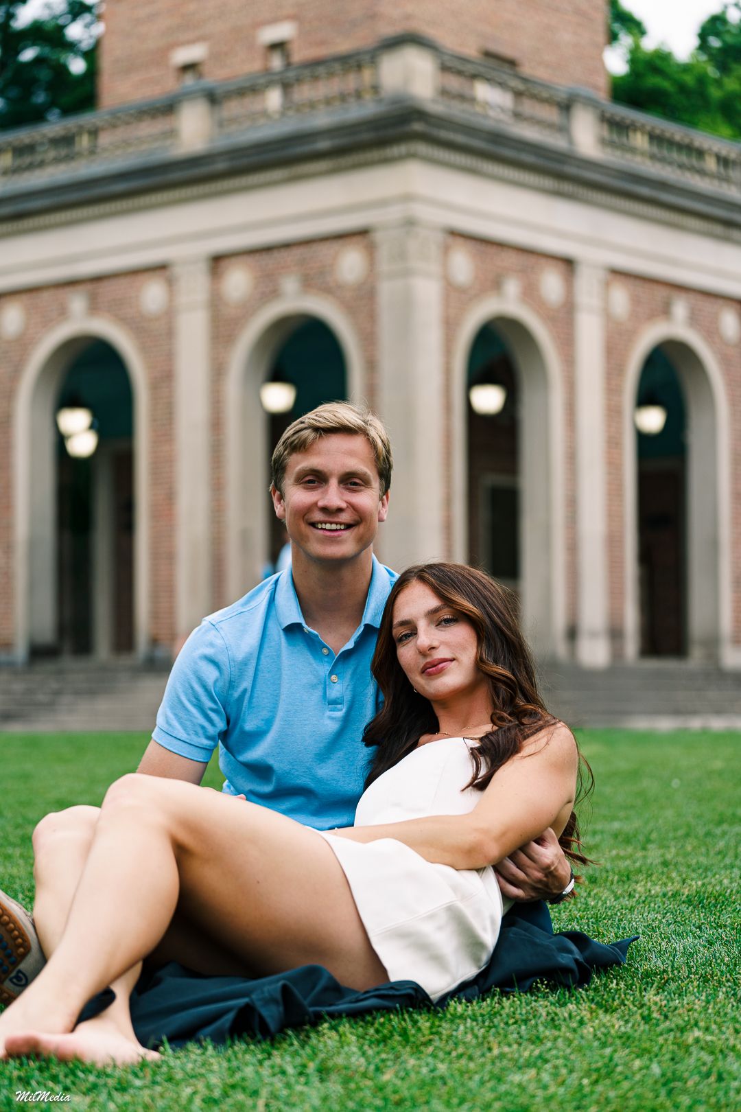 A couple relaxes on the grass in front of the UNC Bell Tower