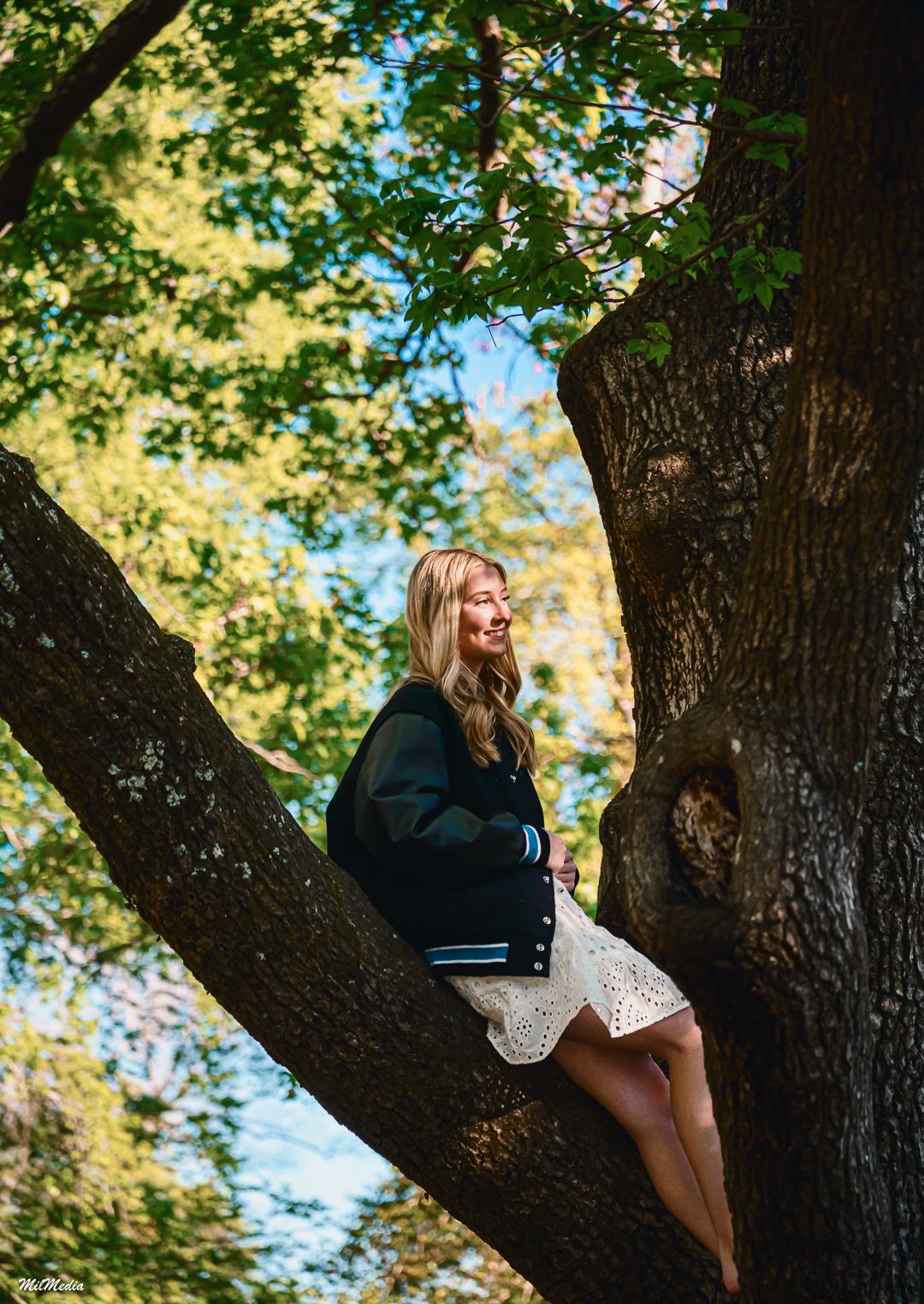 Casual outdoor photoshoot in tree with dappled sunlight through autumn foliage.
