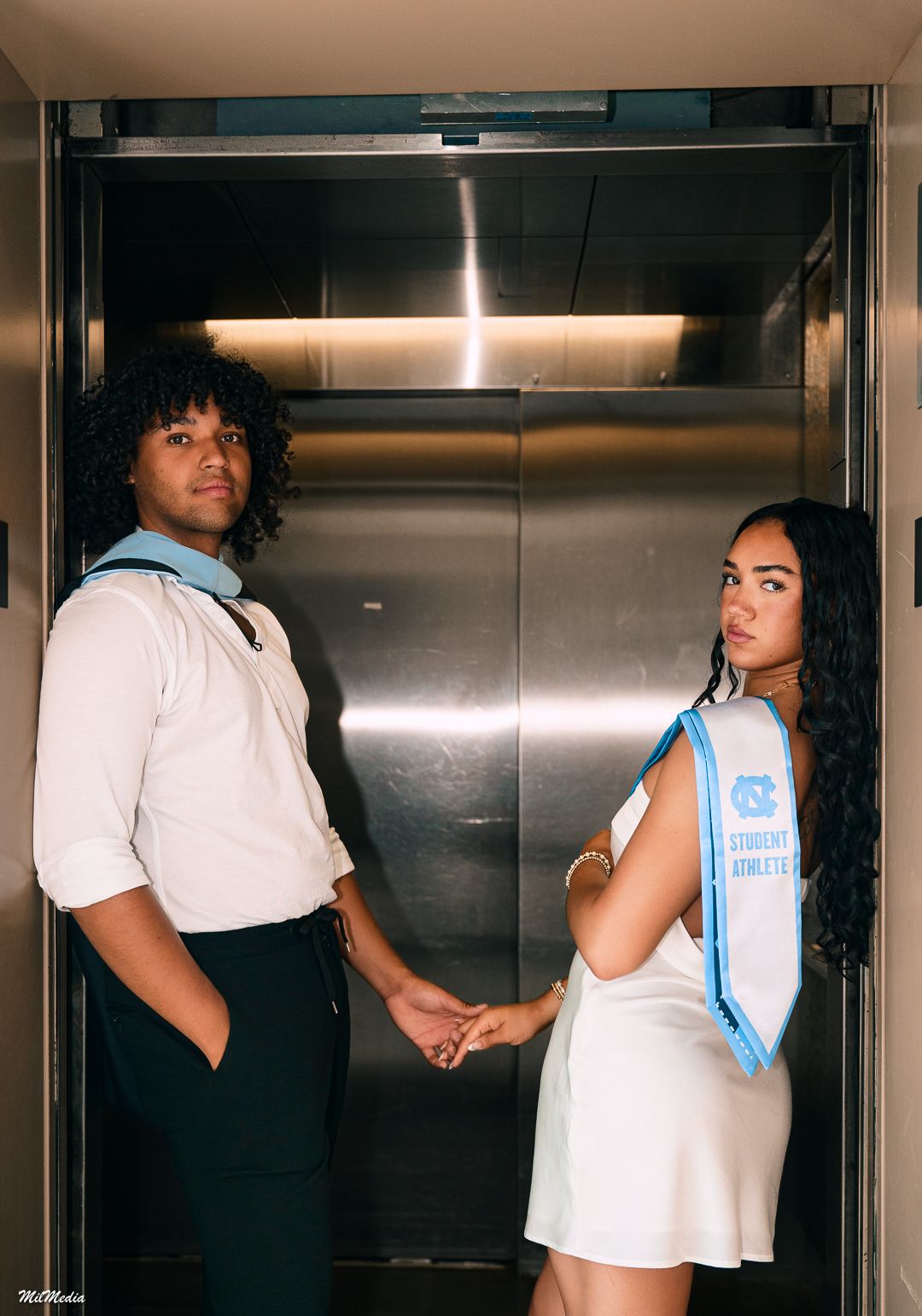 Stylish graduation photo taken in modern elevator with blue and white attire.