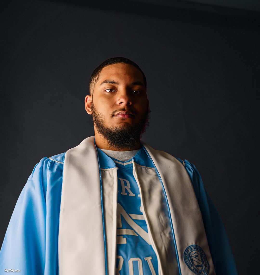 Dramatic side profile portraits wearing light blue and white graduation stole against black background.