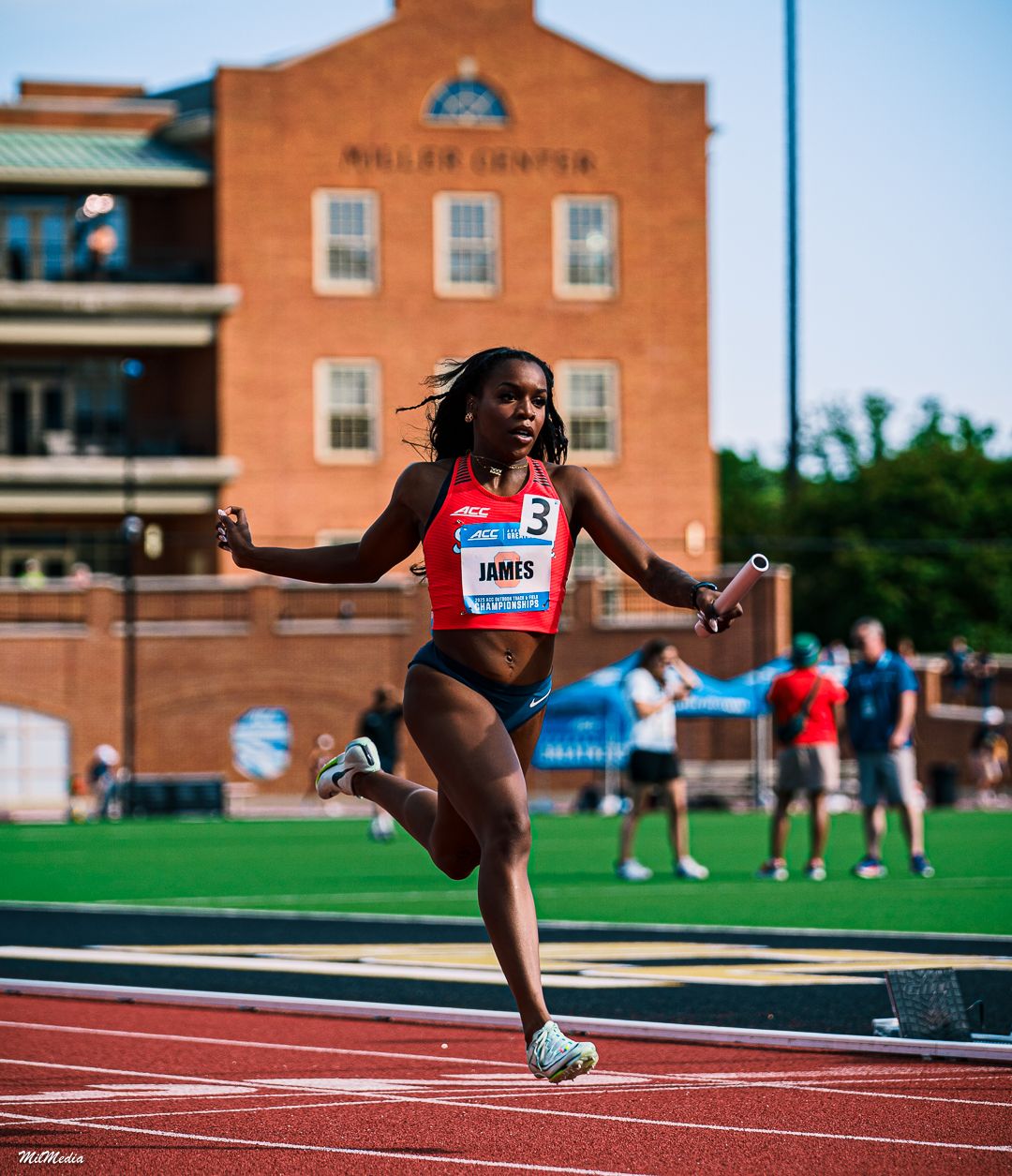 Track athlete in competition uniform sprinting powerfully on outdoor track during the ACC Track and Field Championships.