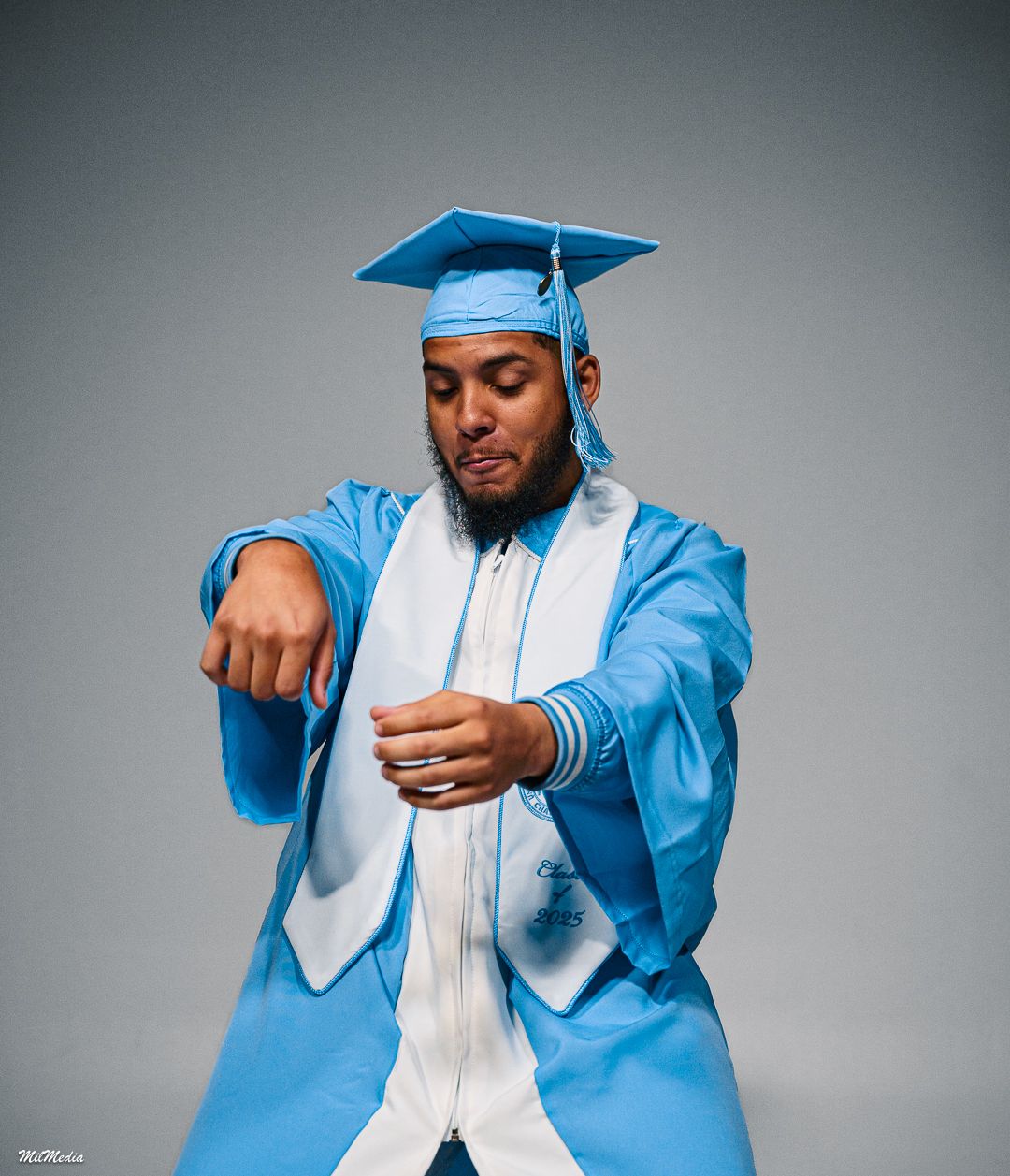 A graduate in UNC regalia strikes dynamic poses against a grey background.