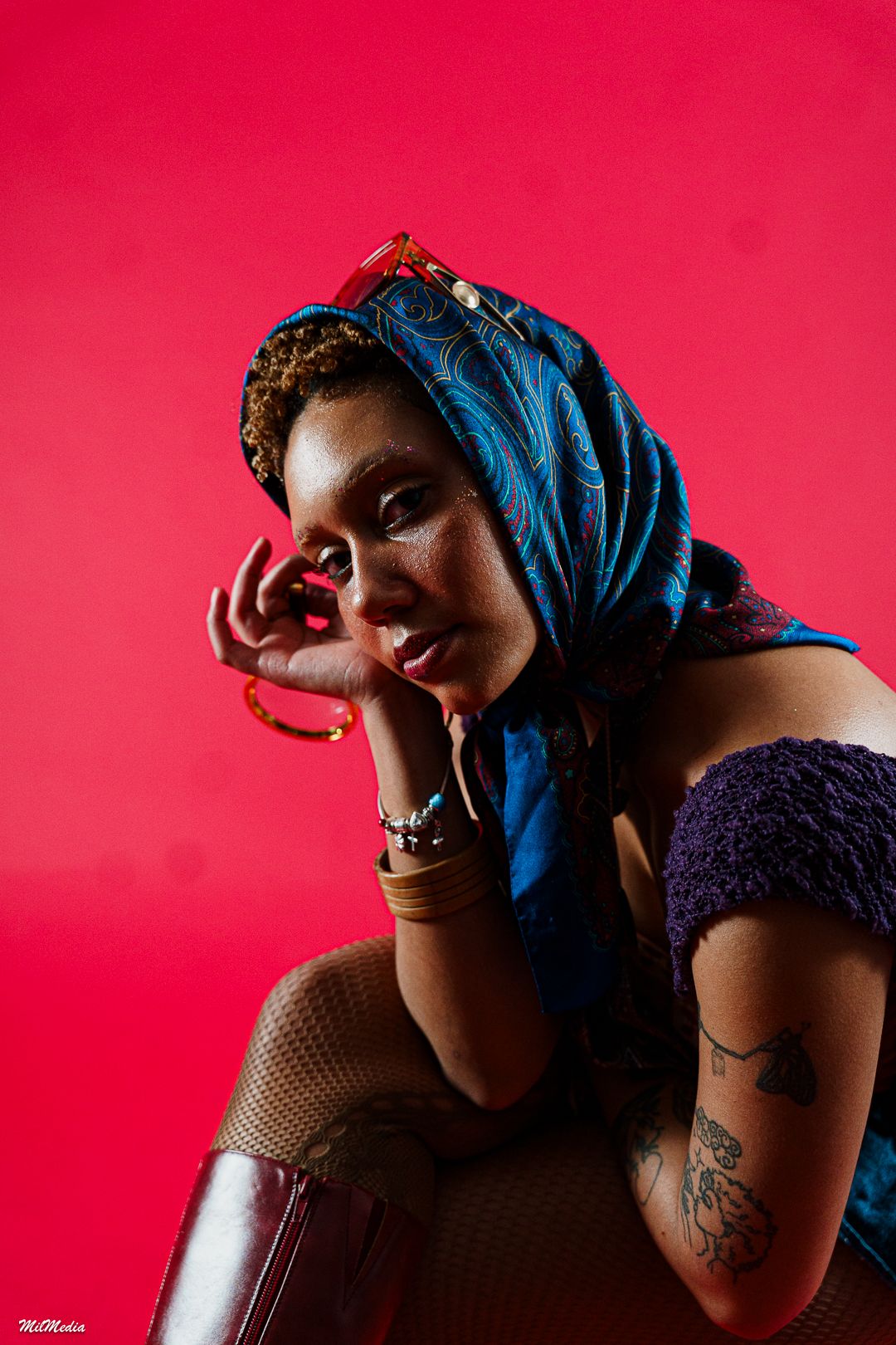 Artistic portrait series with blue headwrap against red studio background.