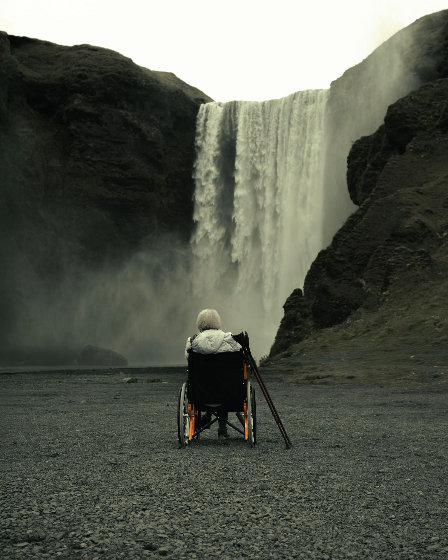 anziana in carrozzina davanti a skogafoss