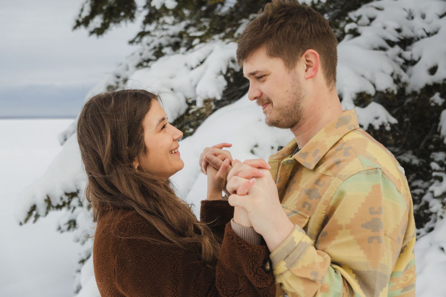 A couple shares tender moments together in a series of romantic outdoor photos against a cloudy sky.