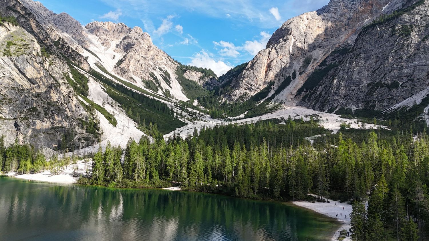 Vue de drone d’un lac avec petites plages entouré de pins et de montagnes