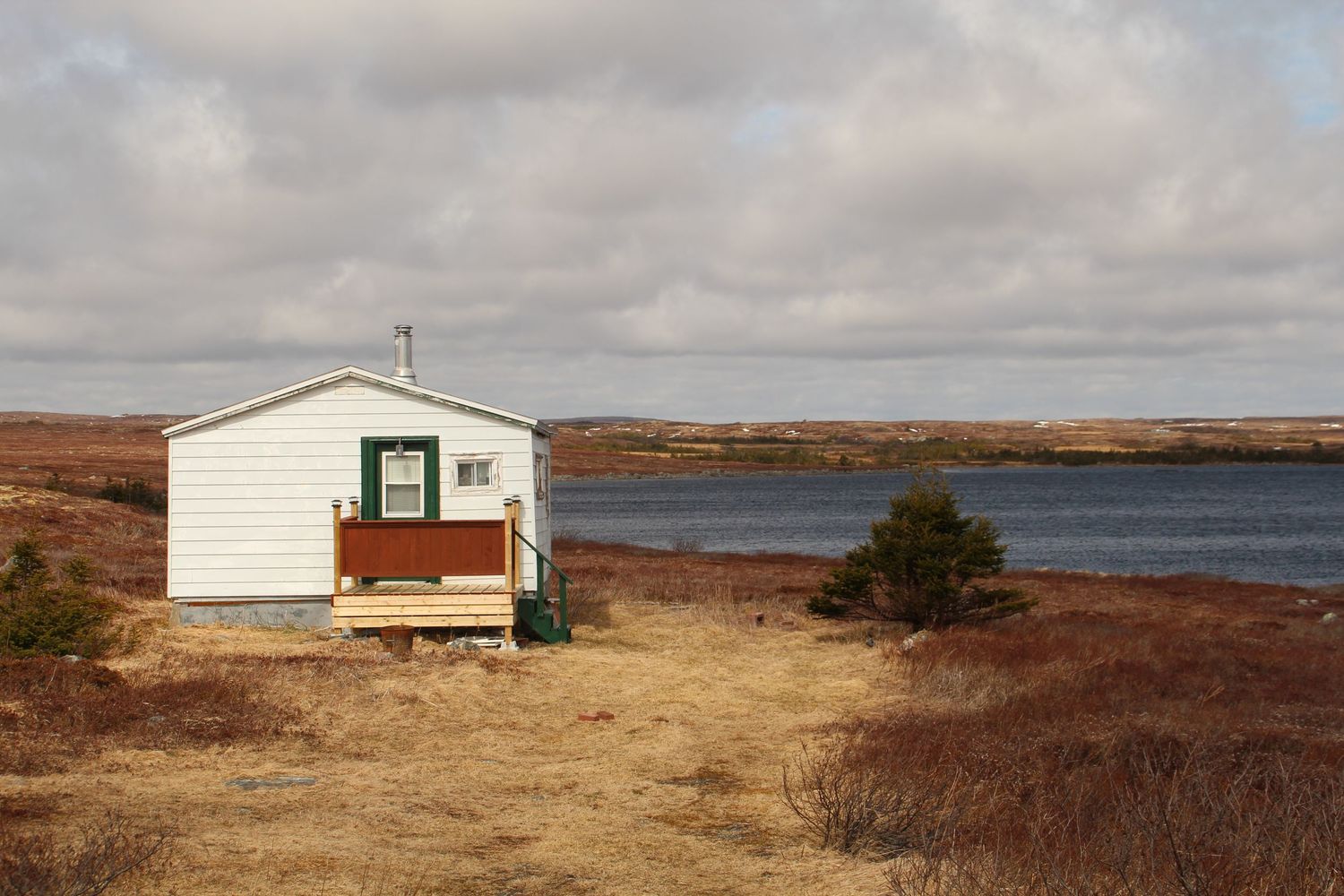Cabane au milieu d’une plaine avec de l’herbe brûlée et un point d’eau