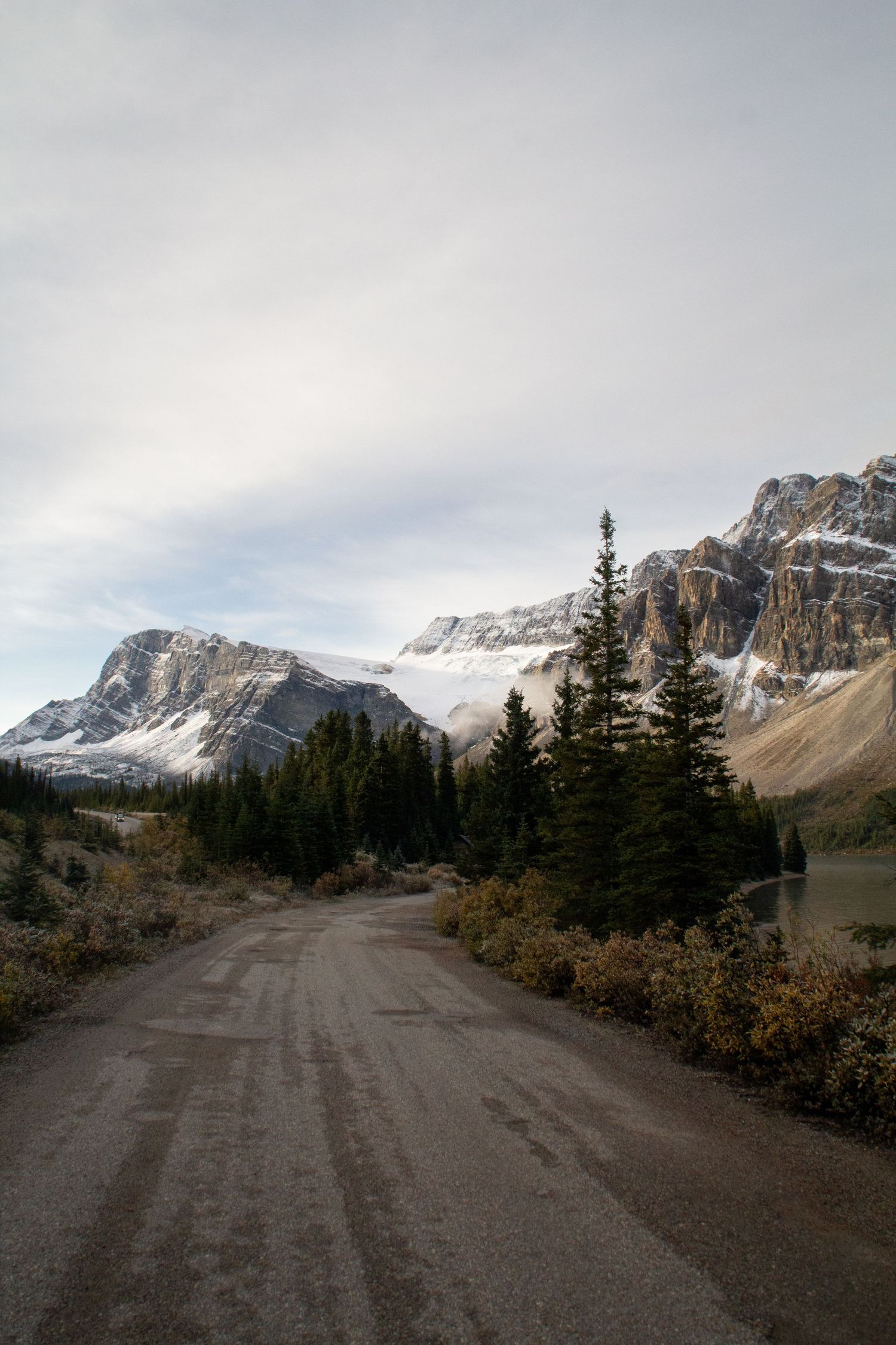 Petite route entre montagnes enneigées, lac et pins