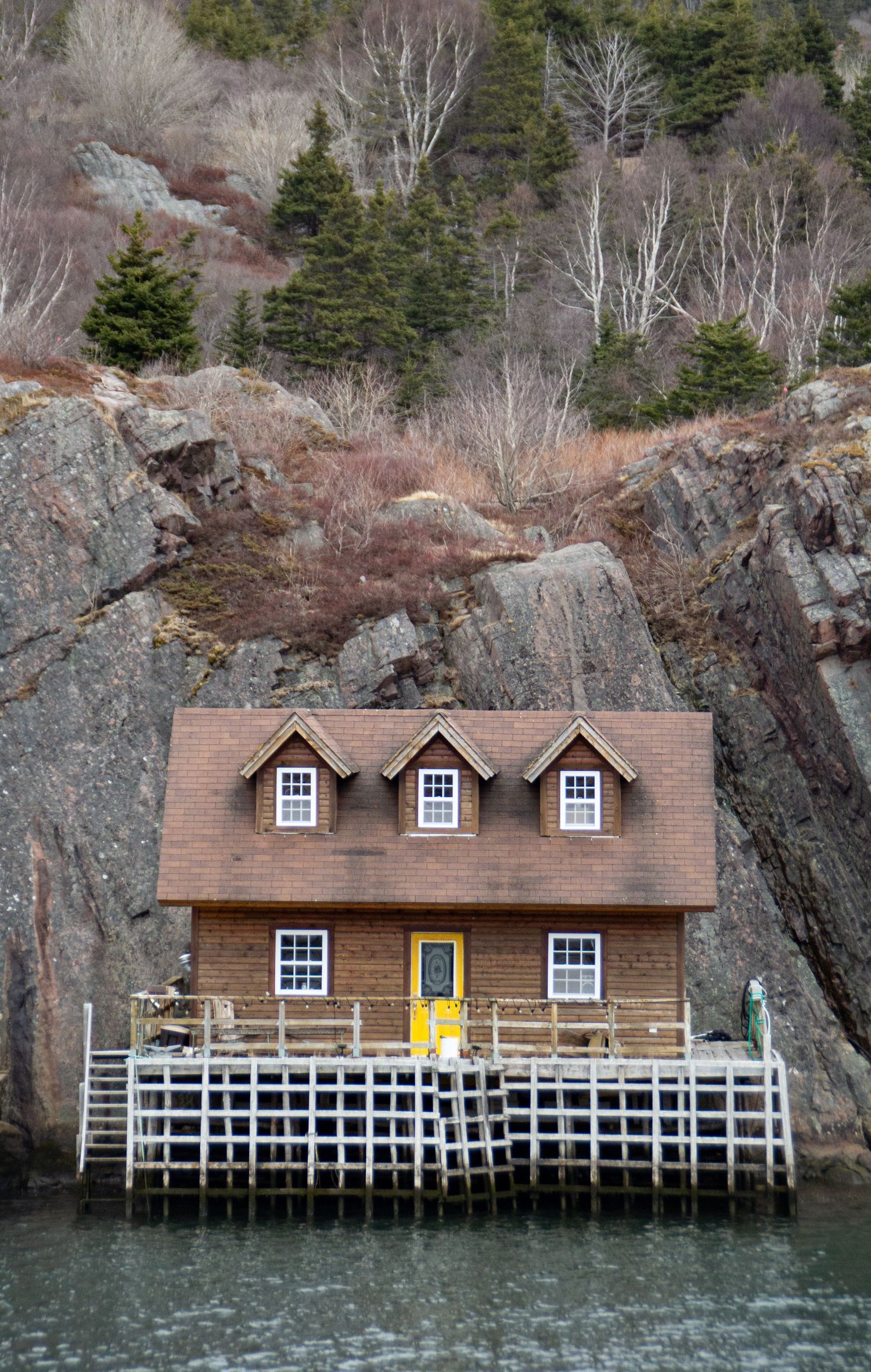 Maison marron sur pilotis avec une porte jaune.