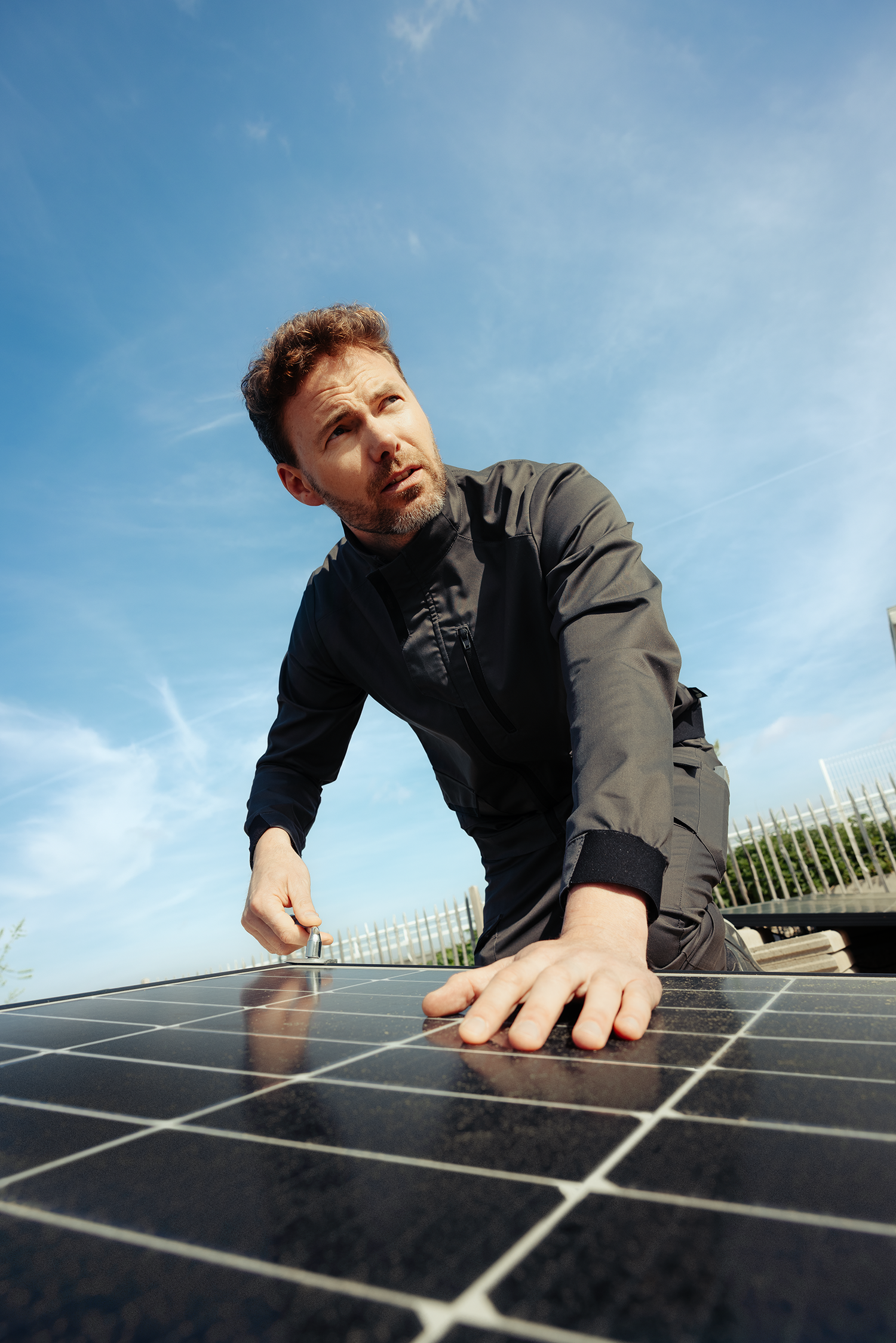 Homme en tenue de chantier Molinel, qui travaille sur un panneau photovoltaïque
