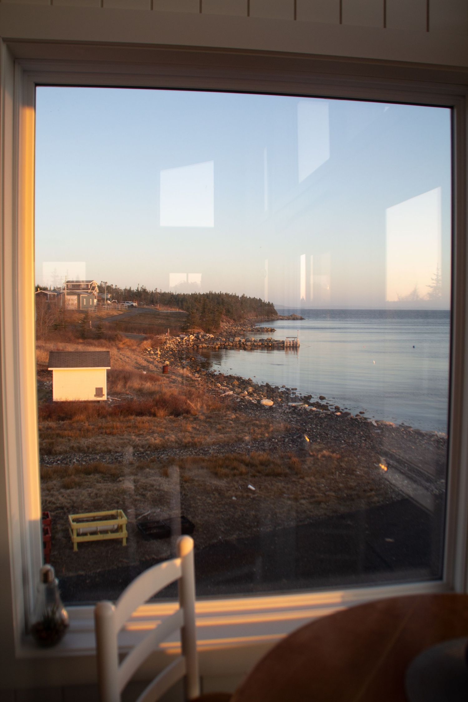 Vue d’une fenêtre montrant l’extérieur en bord de mer au lever de soleil.
