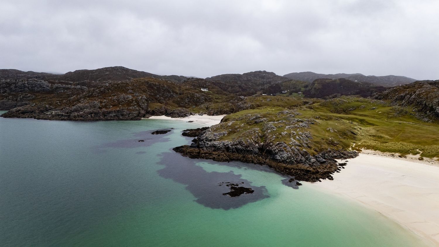 Plage de sable blanc et d’eau turquoise de Lairg en Ecosse avec monts et maison blanche en arrière pl…
