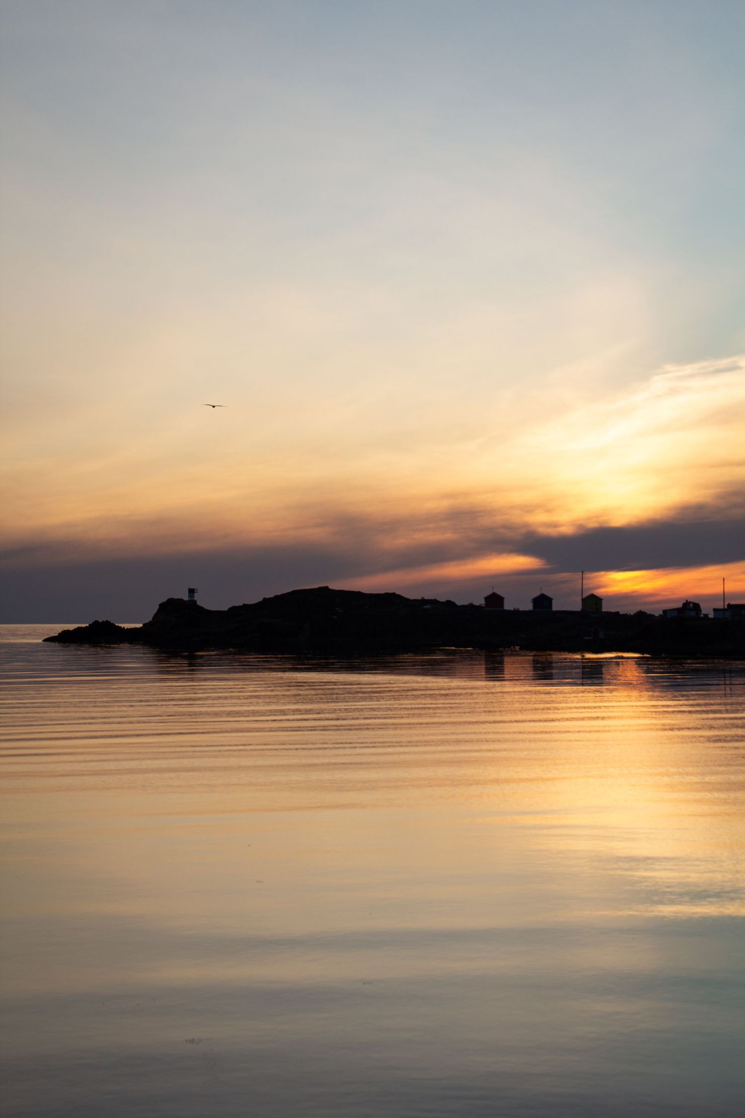 Bande de terre avec cabanes de pêche sous un coucher de soleil.
