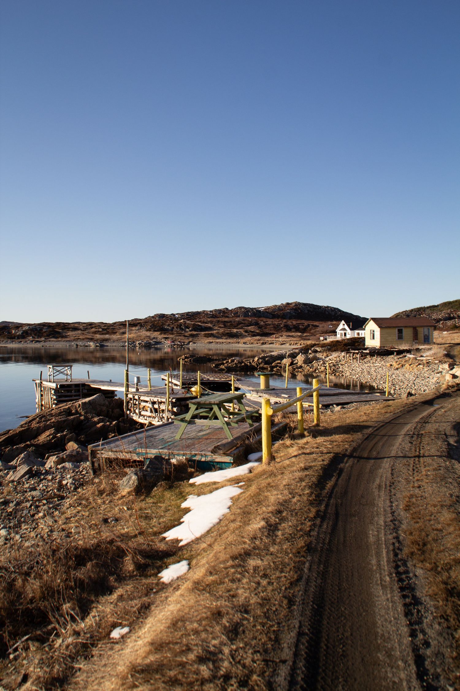 Chemin qui borde la mer avec maisons et installations de pêche.