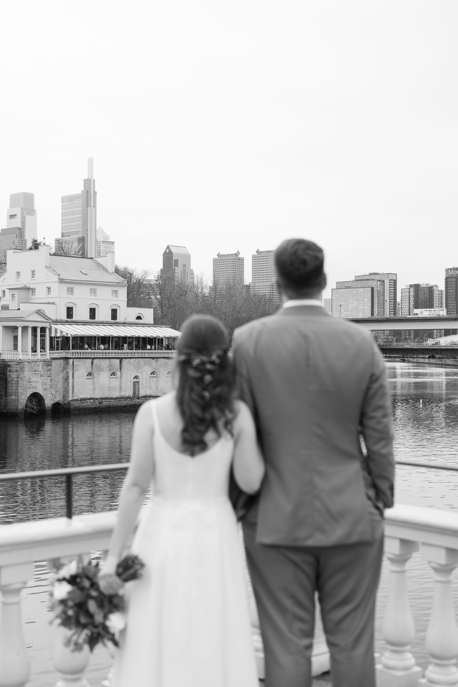 A couple overlooking a city waterfront in black and white wedding attire.