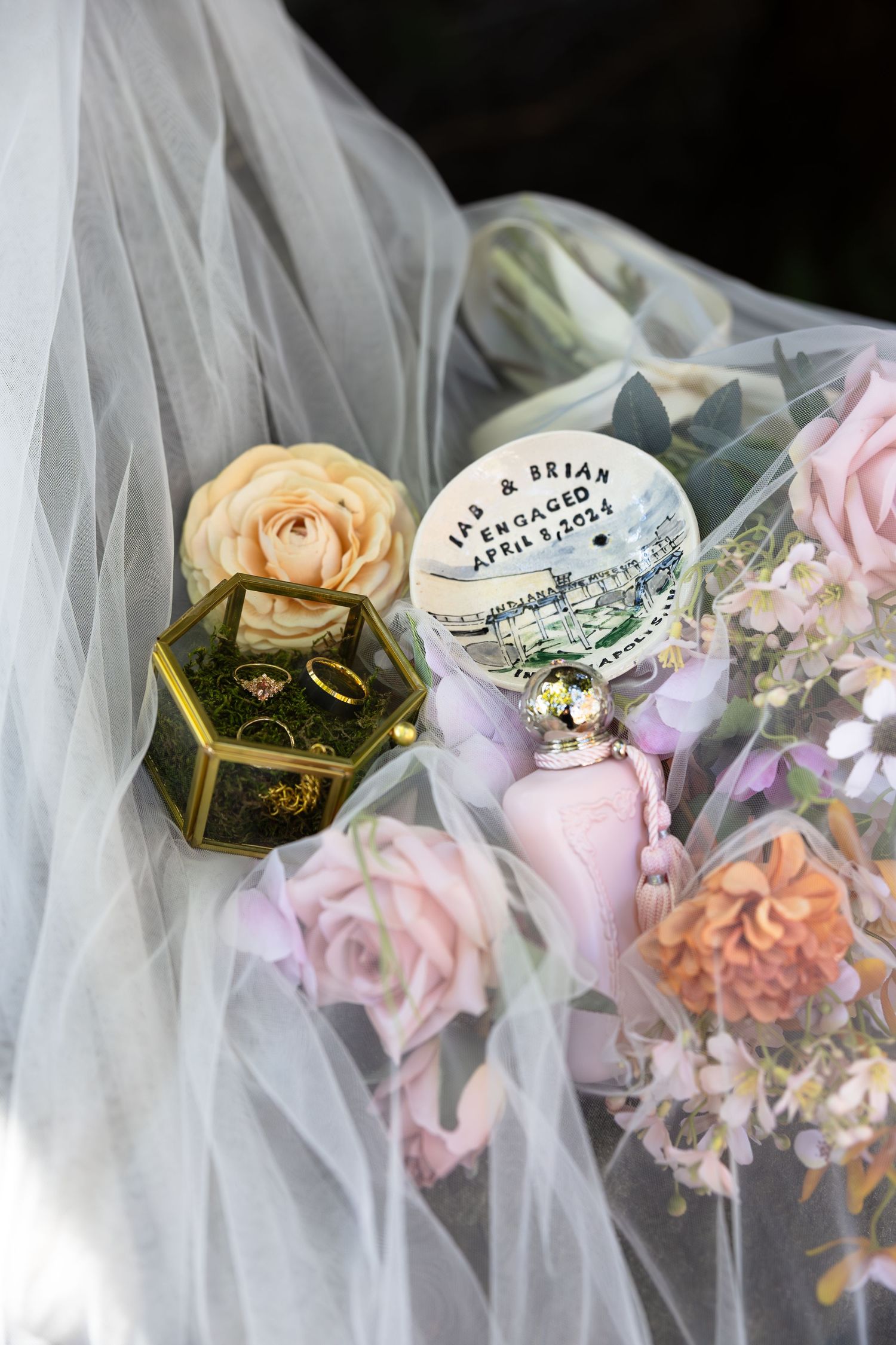 Wedding bouquet details with roses and decorative elements against white veil.