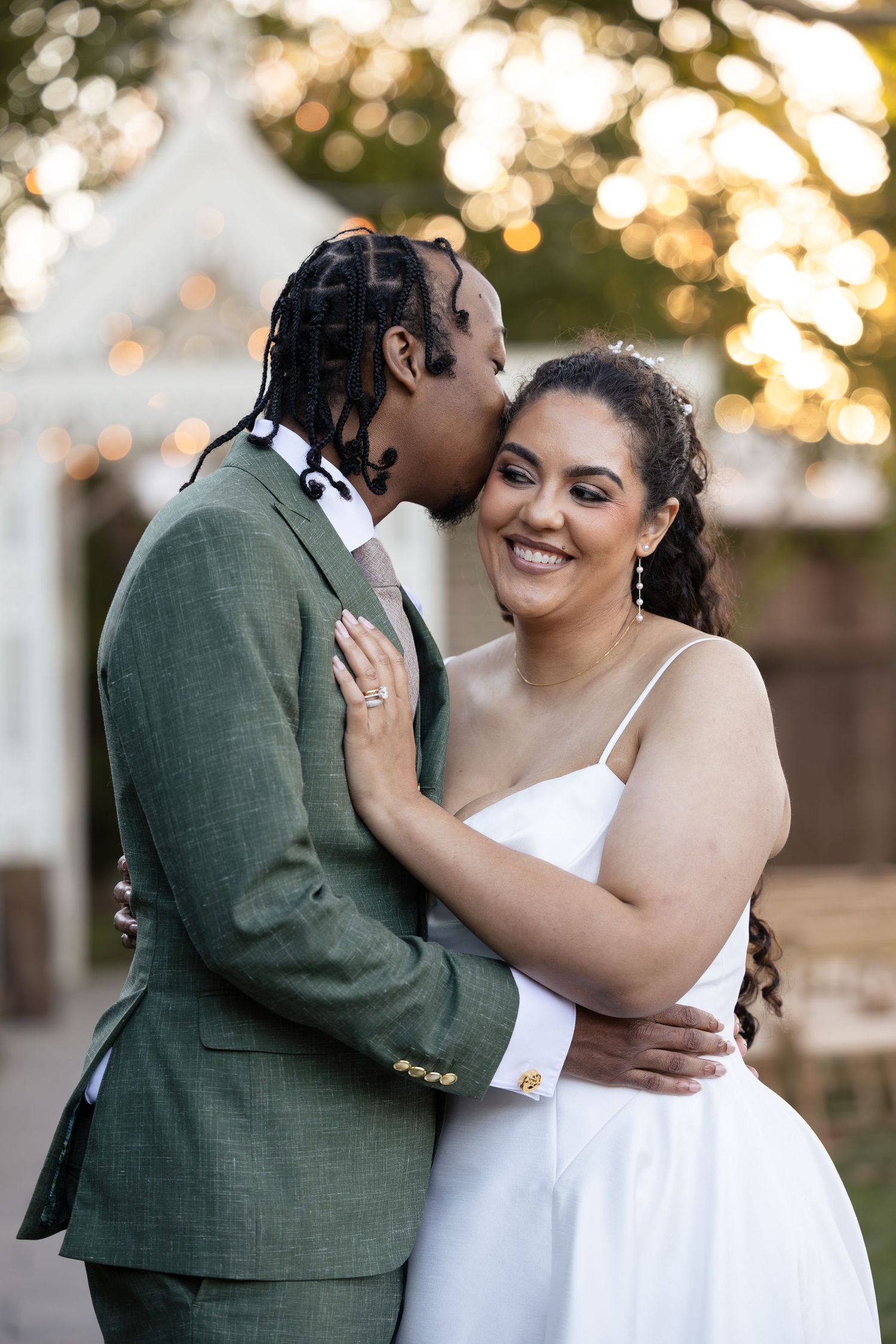 A romantic outdoor wedding photoshoot with a couple embracing in warm sunset lighting.