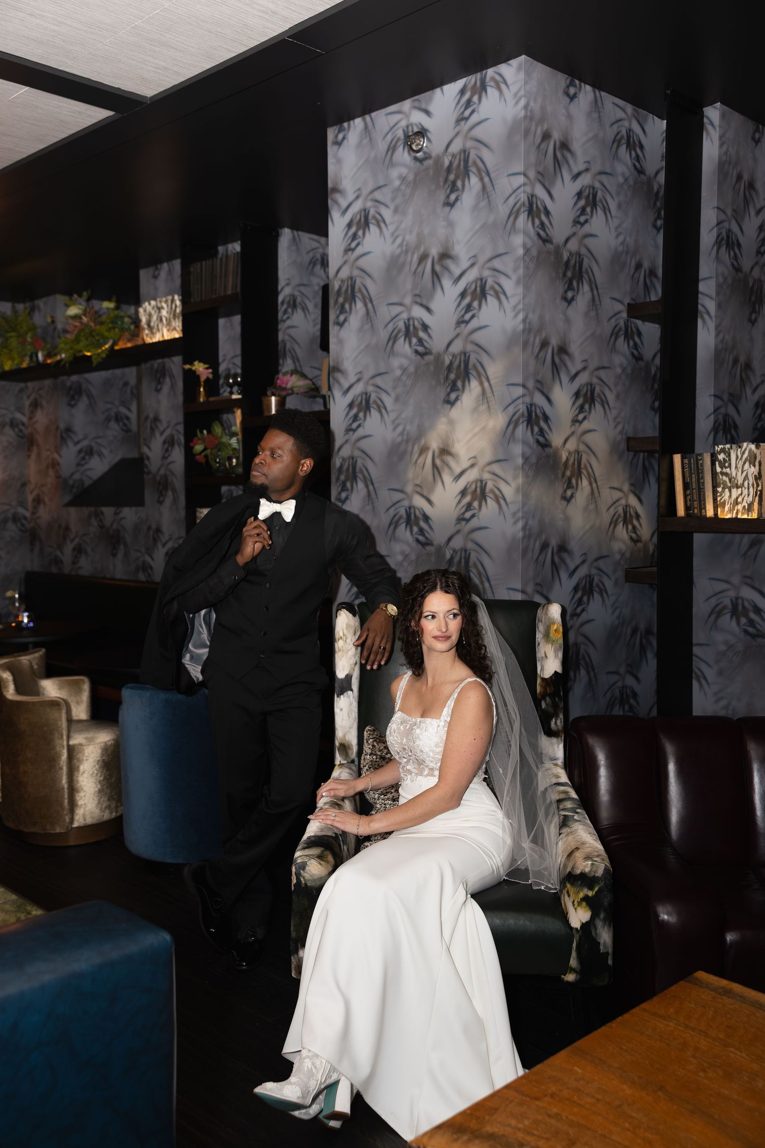 An elegant lounge setting with palm leaf wallpaper and luxurious seating for wedding photos.