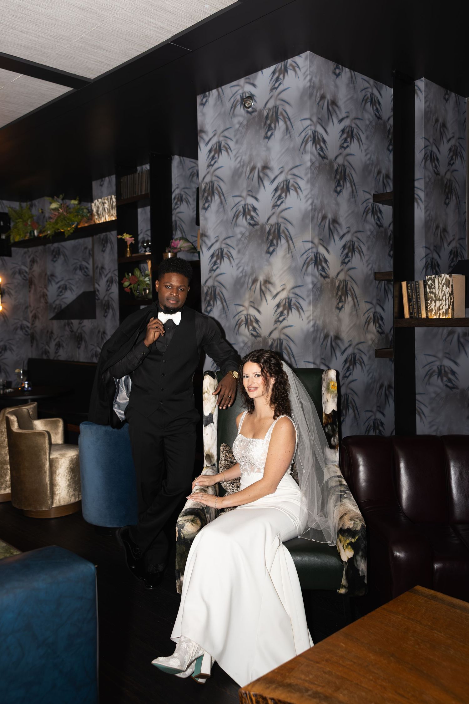 A wedding scene in a modern lounge with decorative palm leaf wallpaper and elegant furniture.