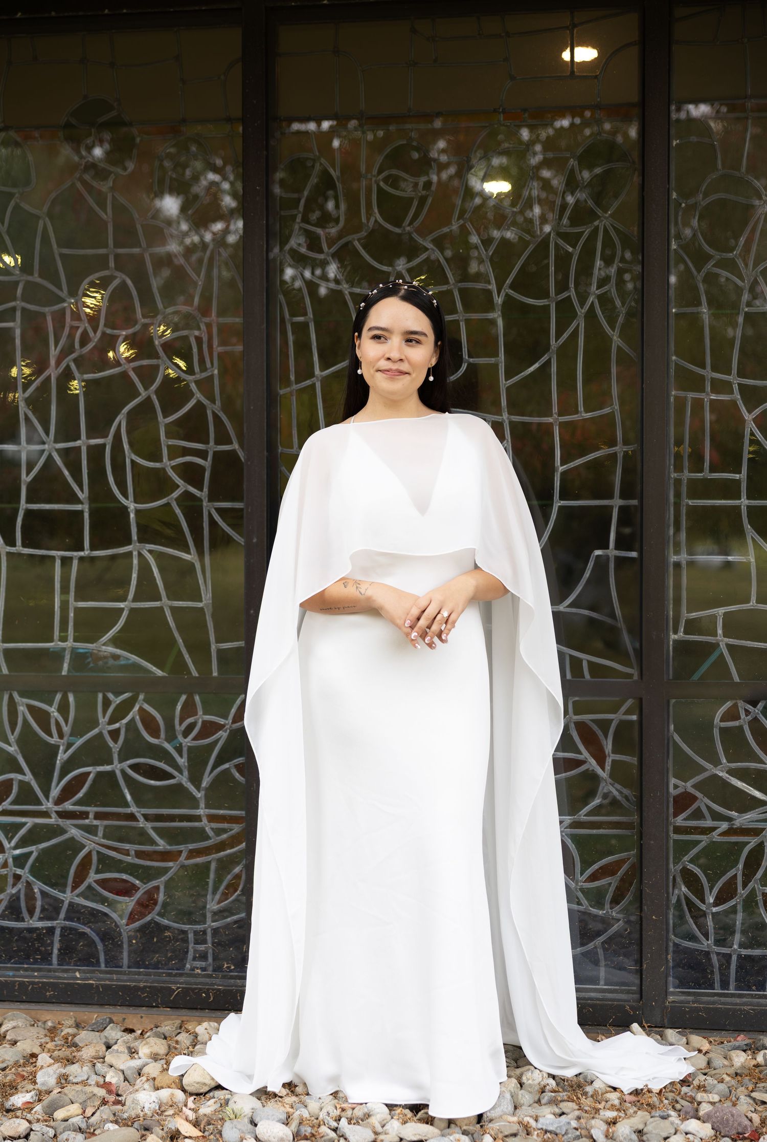 Elegant white cape dress with clean lines and minimalist design against church glass.