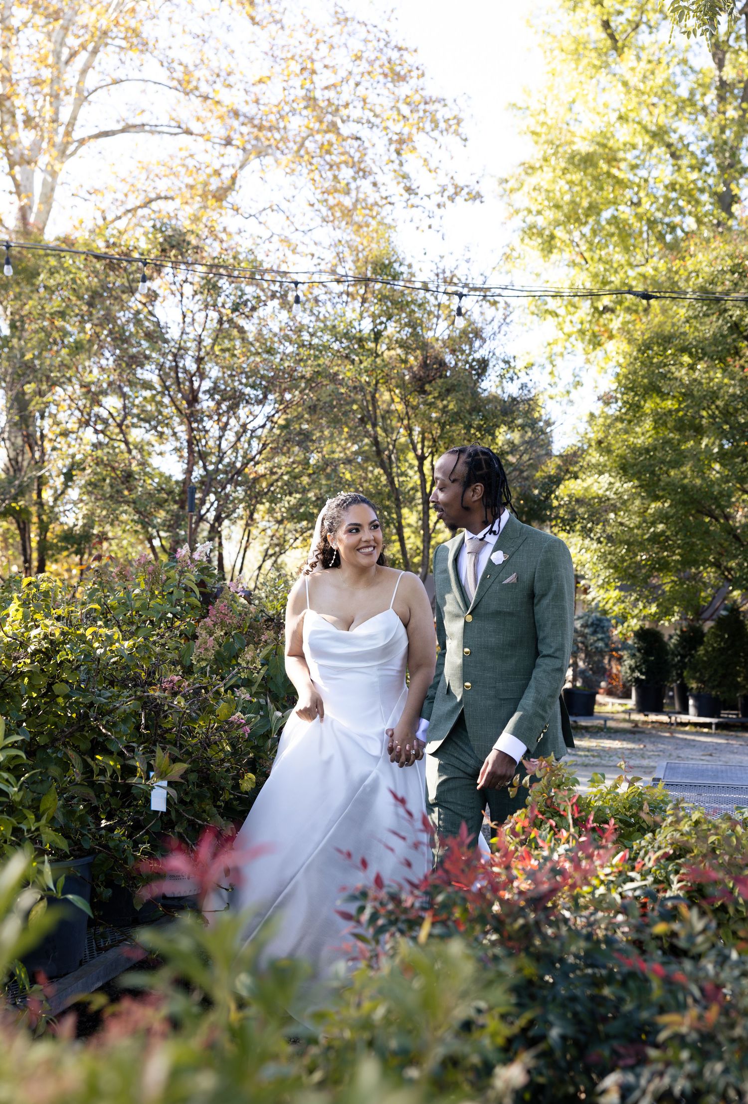 Wedding couple shares intimate moment among blooming garden flowers on autumn day.