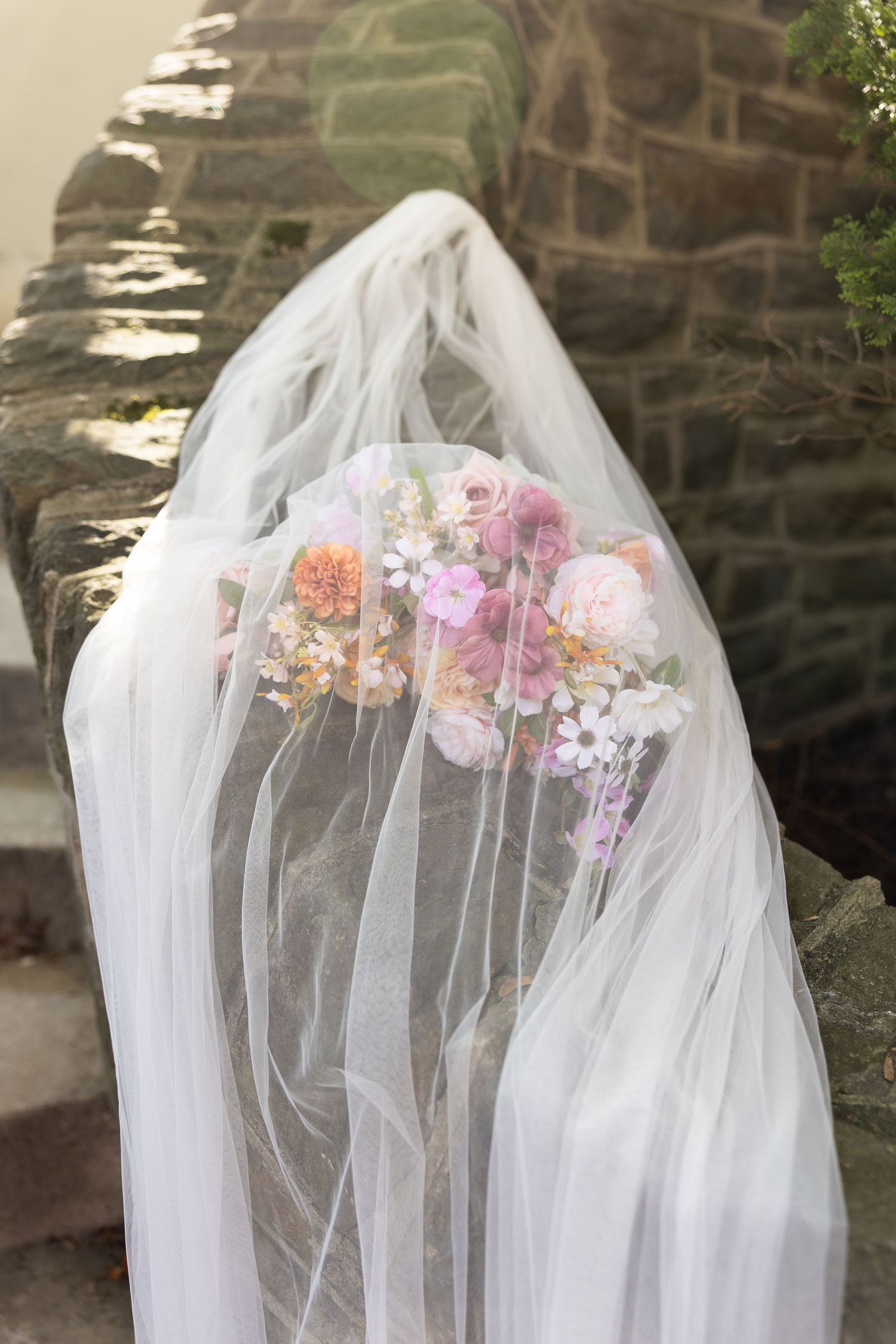 Flowing white bridal veil adorned with delicate pink and peach floral arrangements.