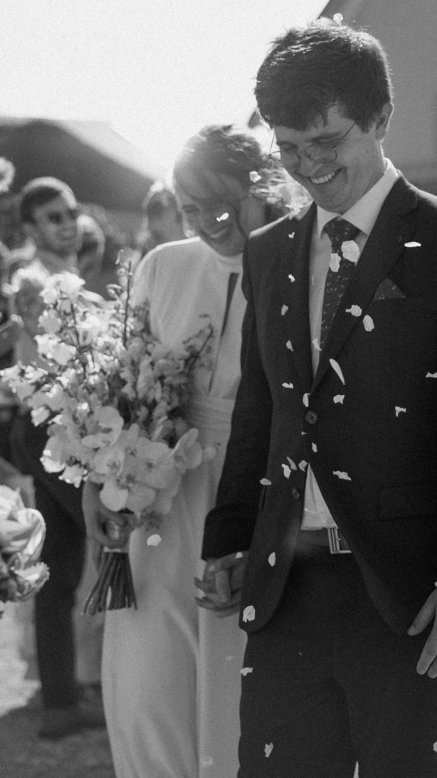 Bride and groom walking hand in hand through confetti after wedding ceremony in chapel in Eastern Cape