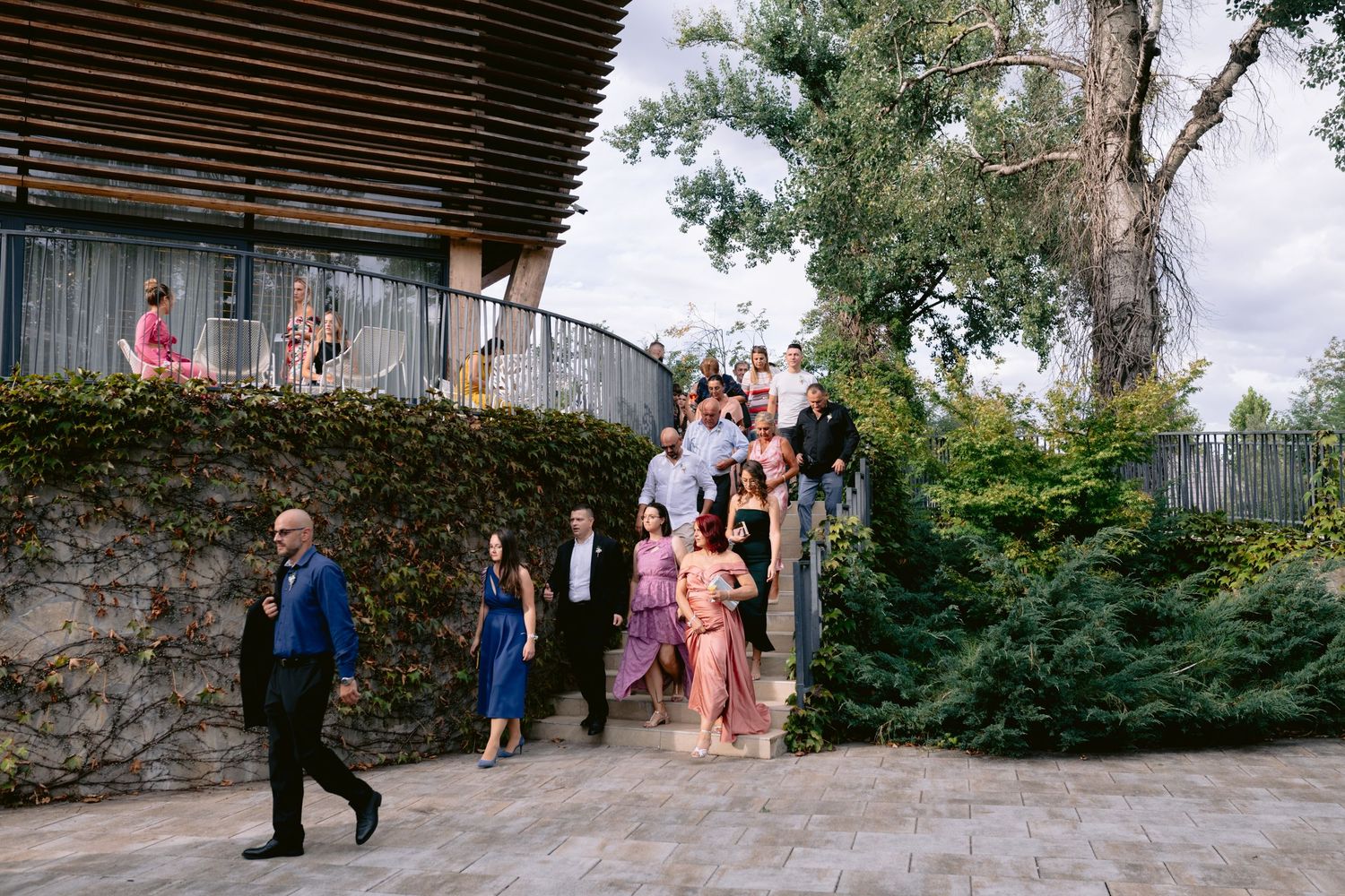 Wedding guests descending outdoor stone steps surrounded by lush greenery at an elegant venue.