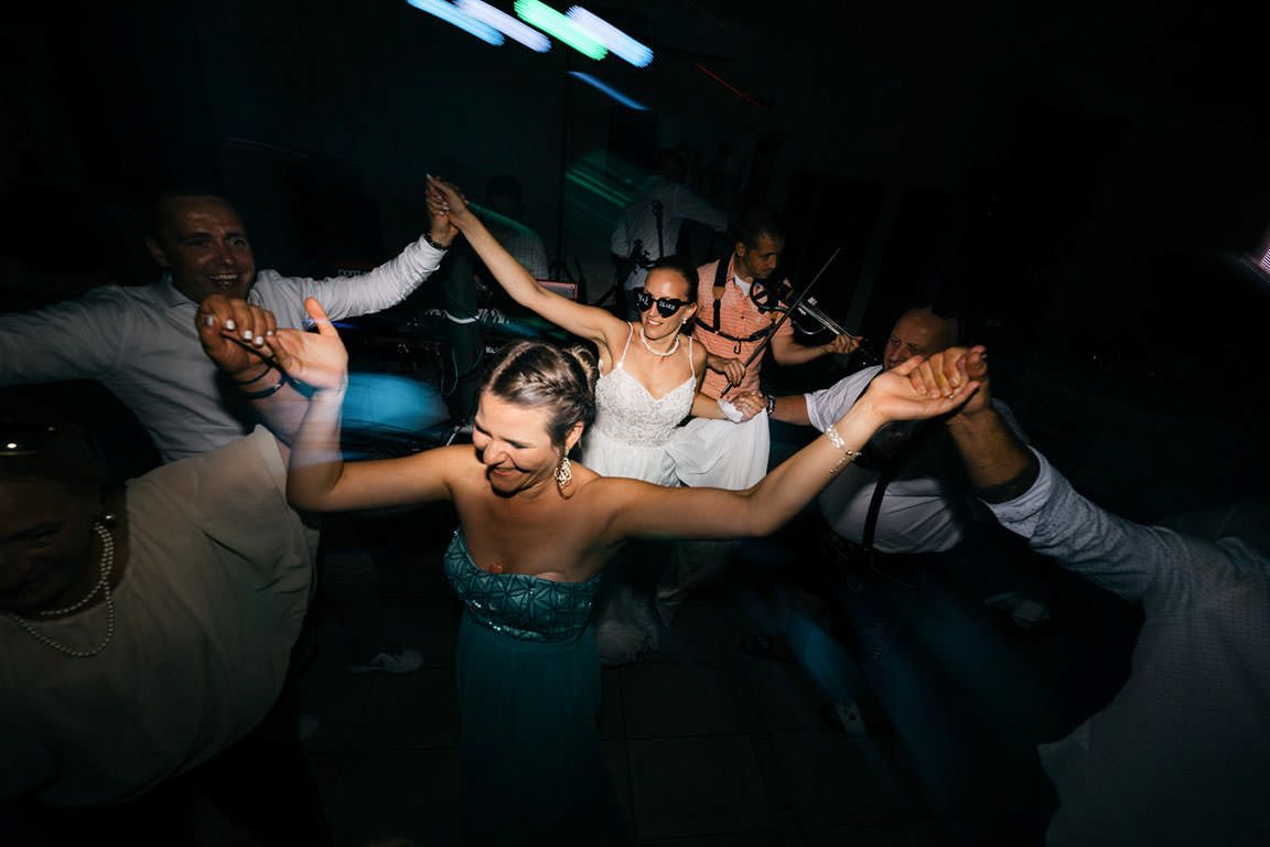 Wedding guests dancing in dramatic lighting at nighttime celebration.