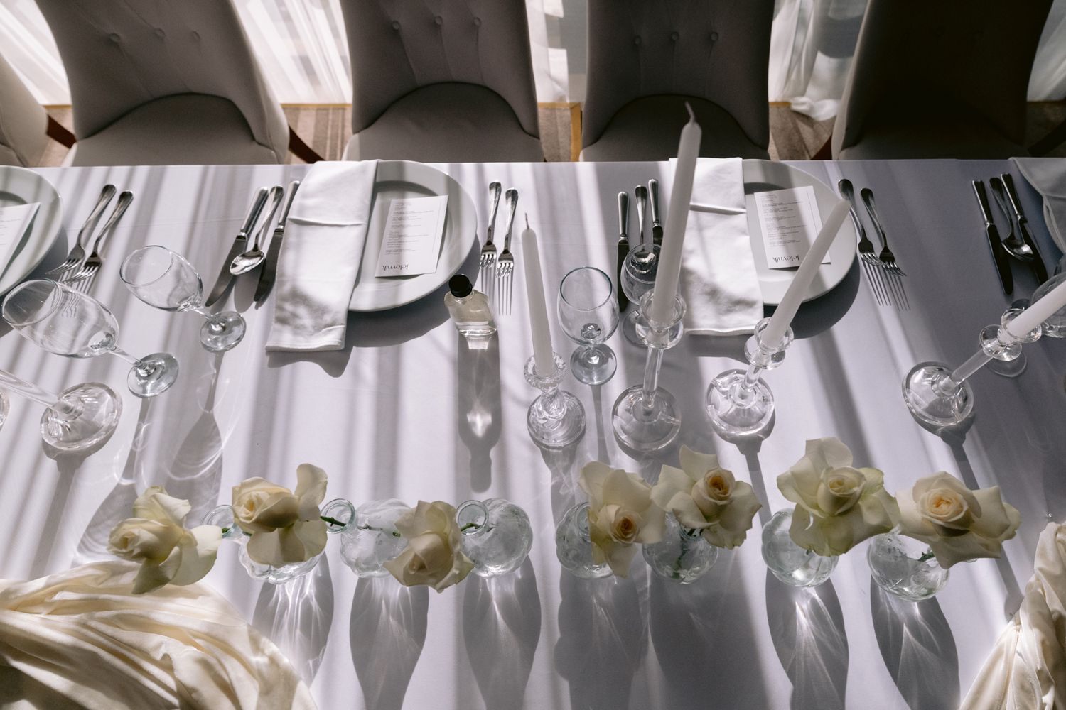 Elegant table setting with silverware and white flowers arranged in uniform pattern.
