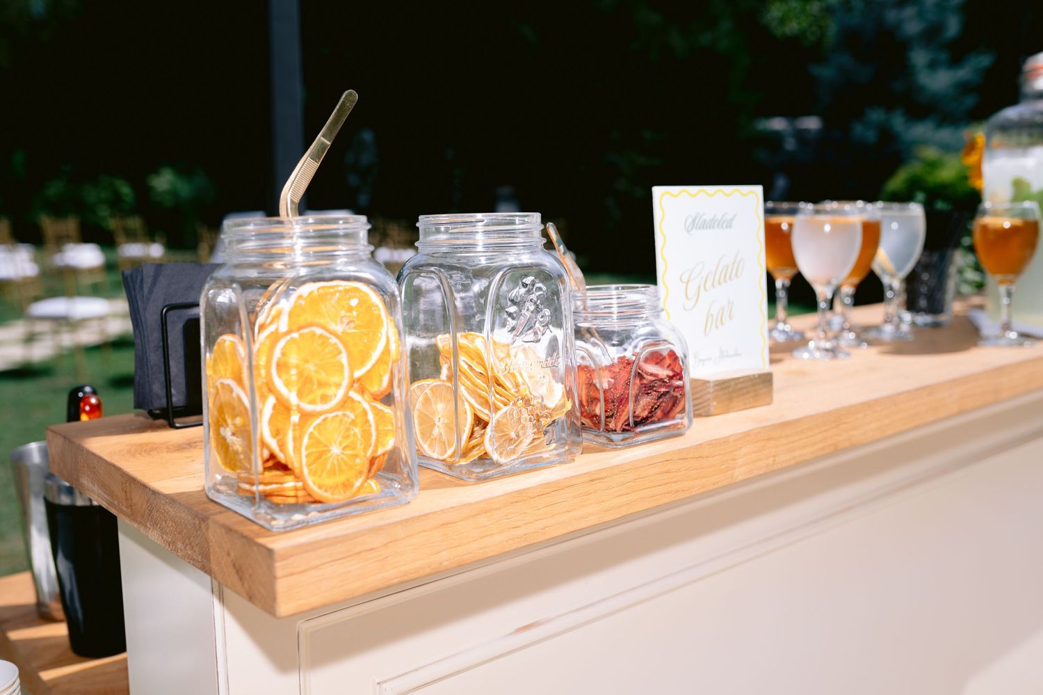 Rustic wooden drink station with glass dispensers and mason jars at an outdoor event.