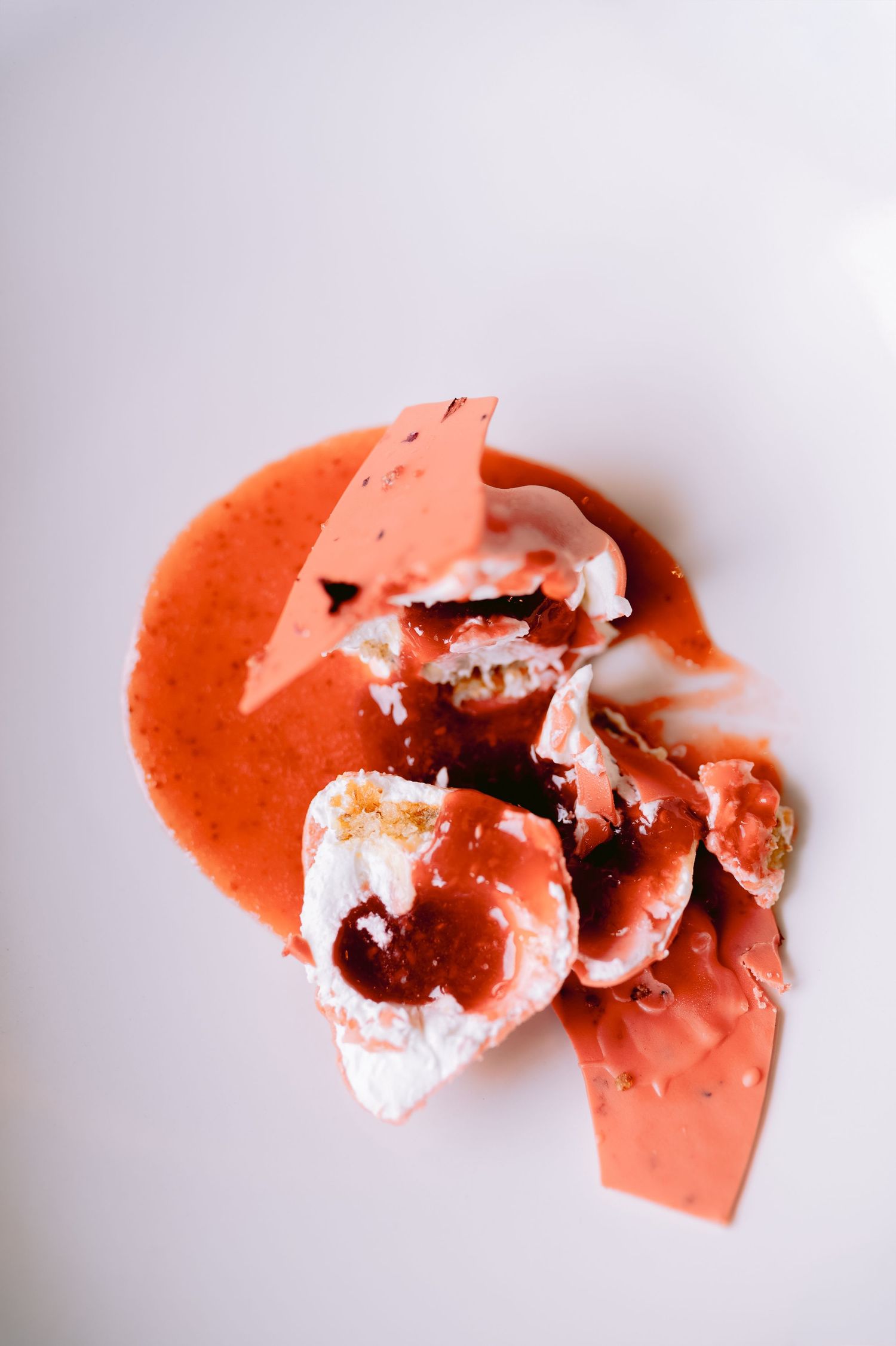Broken pieces of pink meringue or macaron scattered on white surface.
