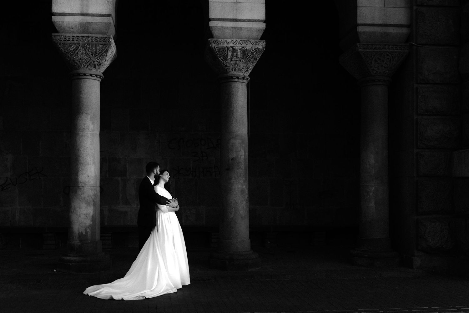 Elegant architectural columns frame a silhouetted figure in a flowing white wedding dress.