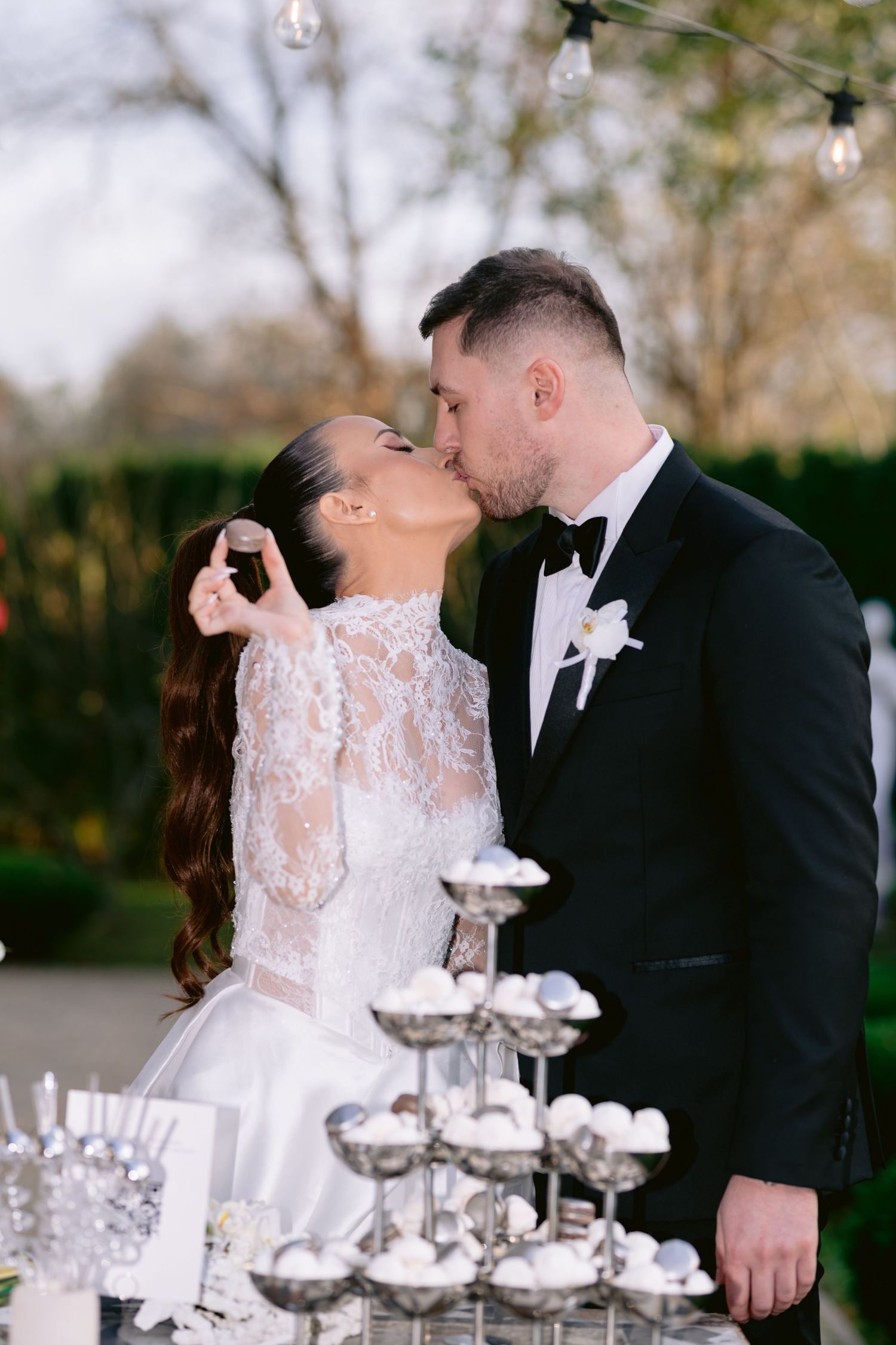 Newlyweds share a romantic moment behind a champagne tower at their elegant outdoor wedding reception.