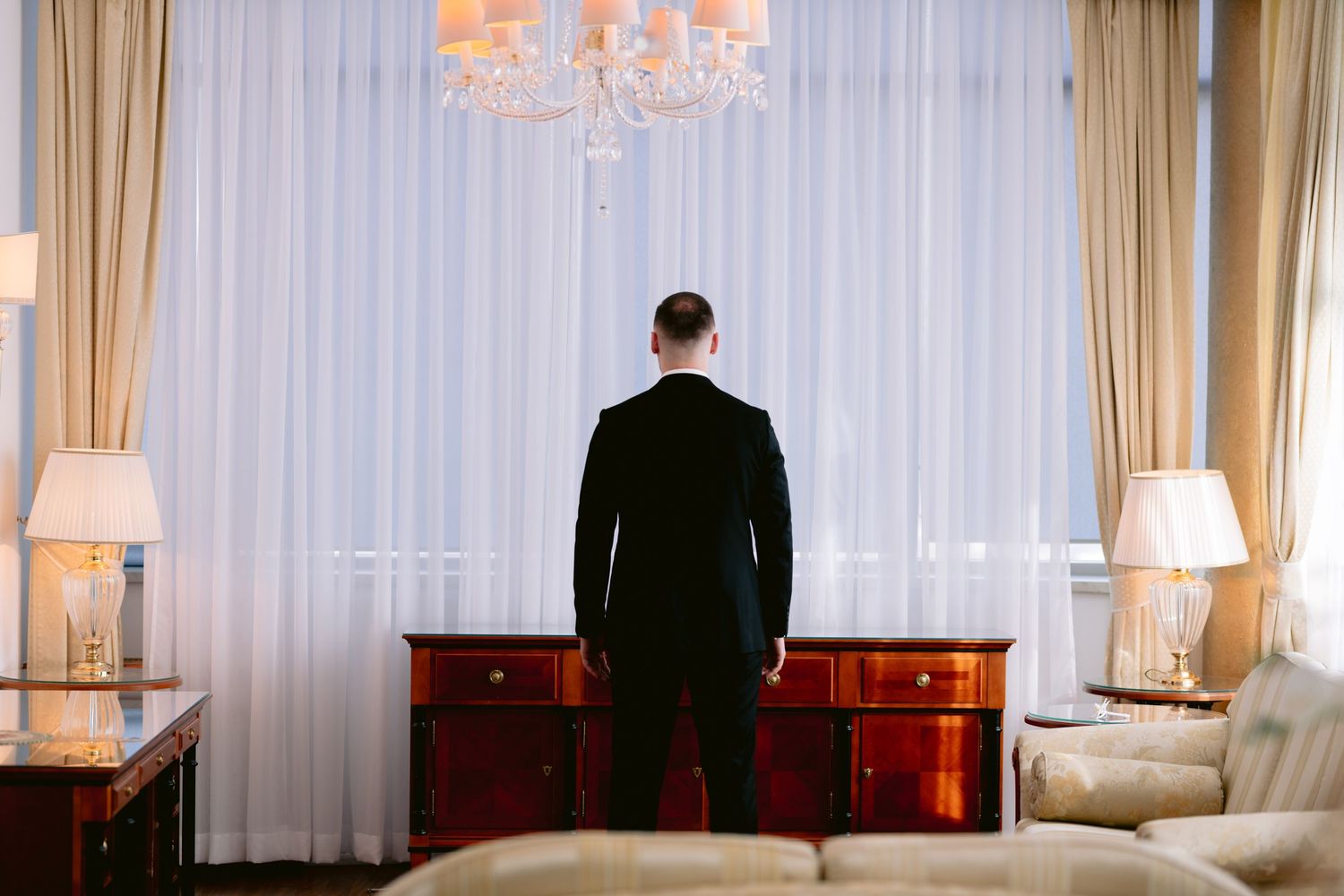 A series of four elegant hotel room interior photos showing ornate rugs, chandeliers and classic furniture in warm tones.