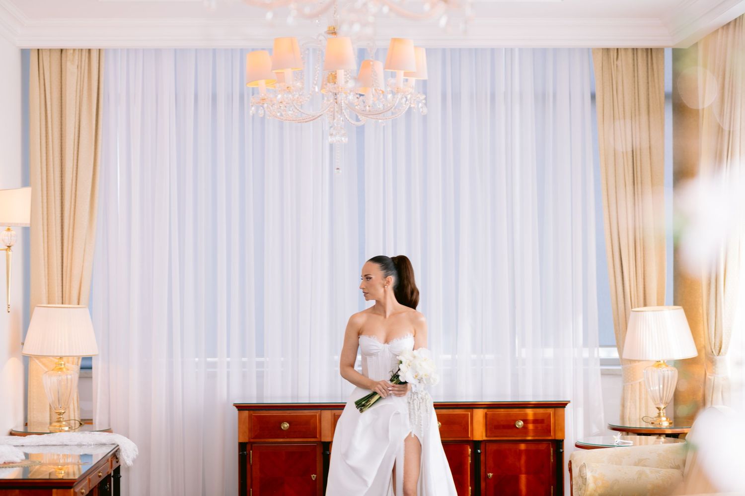 Elegant bridal preparation scene in a bright, luxurious hotel room.