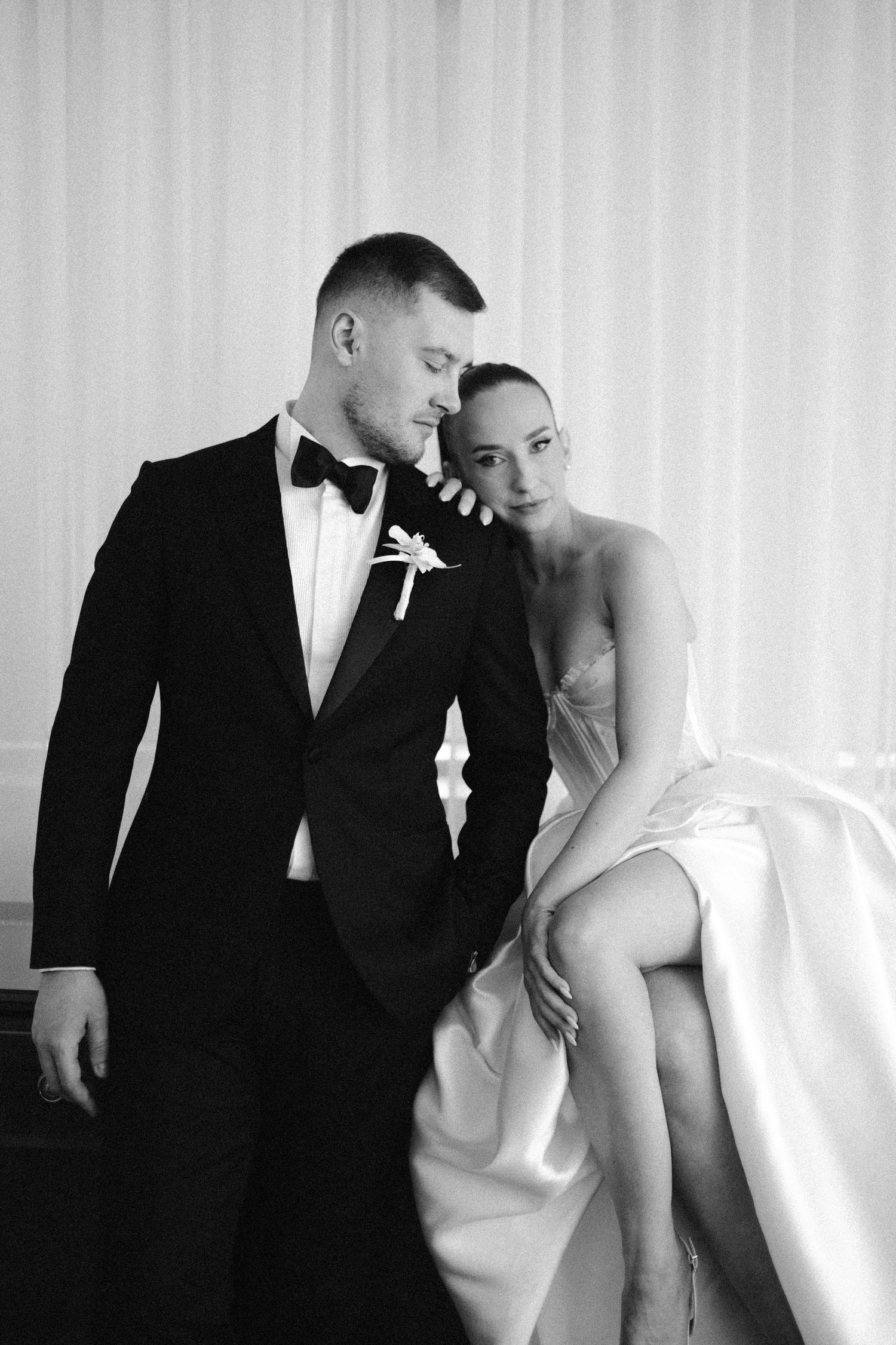A black and white wedding photo series showing romantic poses between a couple in formal attire.