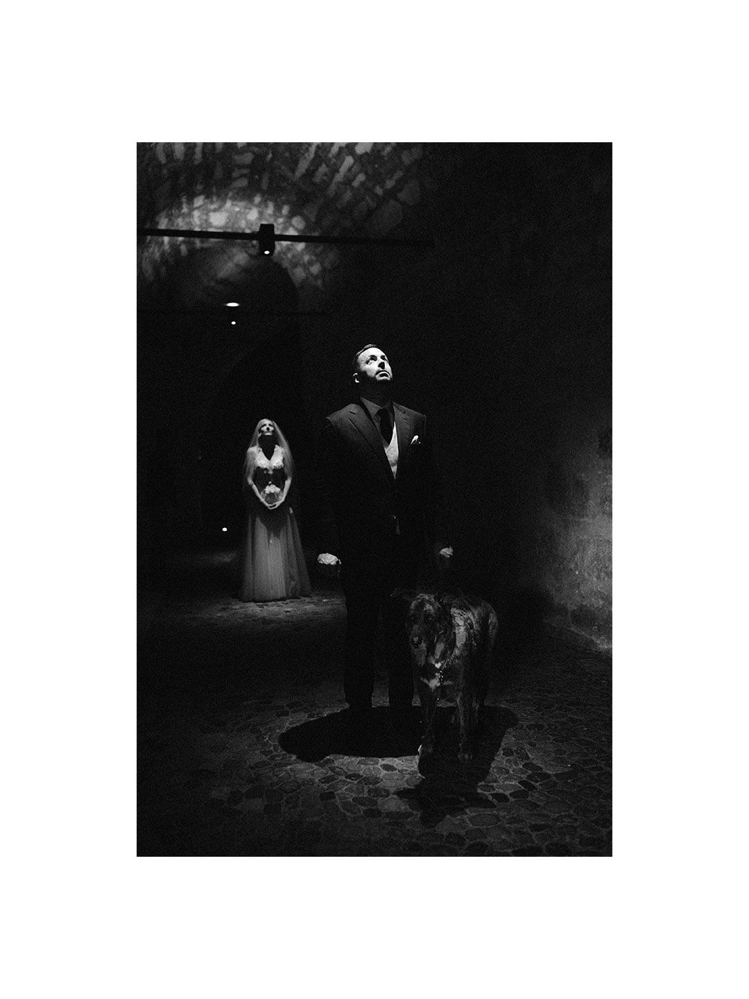 Crno-bijela fotografija mladoženje sa psom u tamnom tunelu dok mlada stoji u pozadini Schaffhausen.