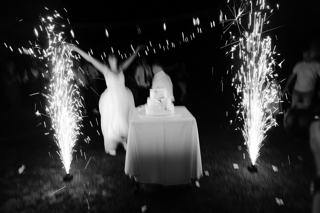 Sequence of white sparkler fountains creating dramatic light effects against a dark background.