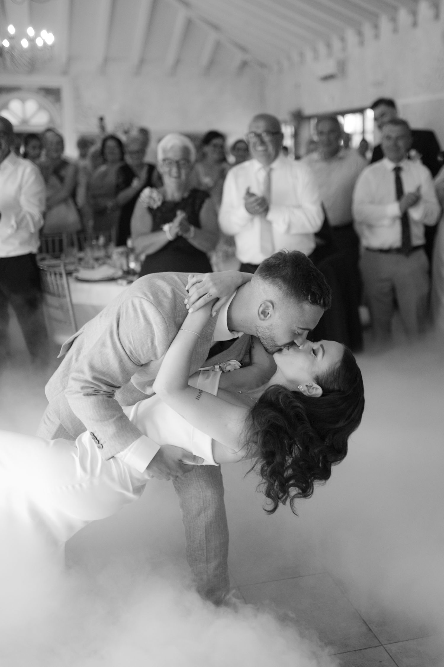 Romantic couple dips and dances in a dreamy white ballroom filled with fog effects.