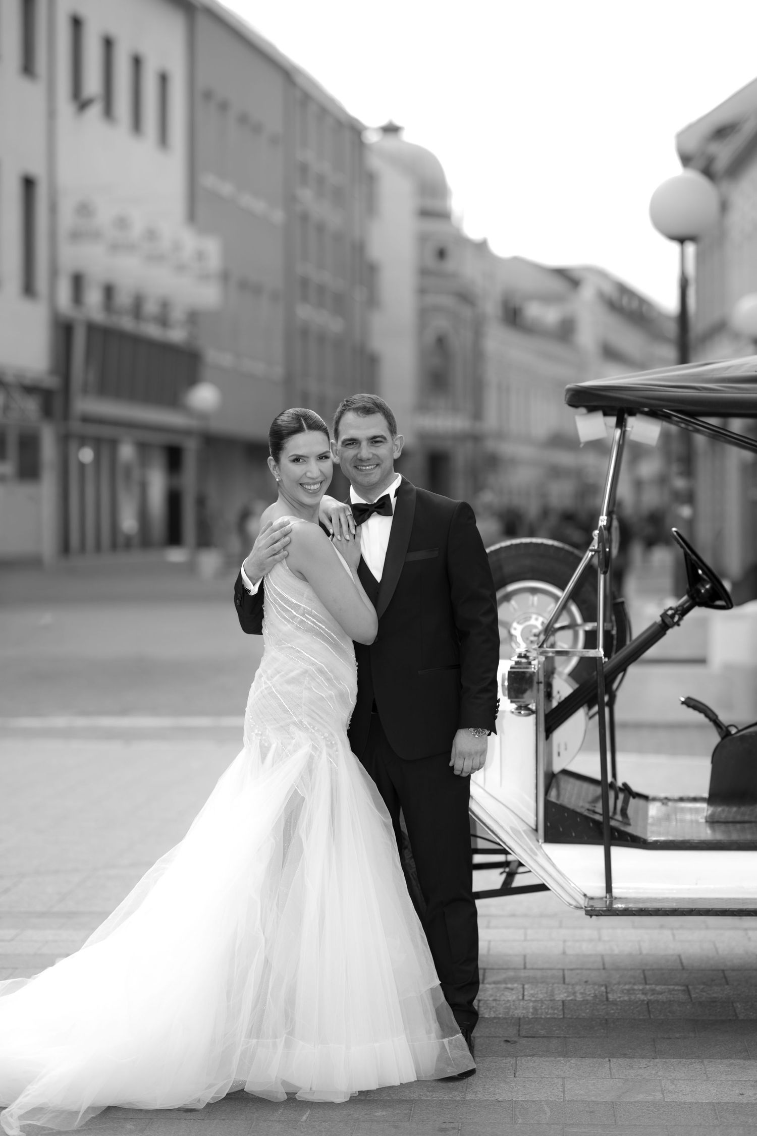Black and white wedding portraits of a couple posing on an urban street.